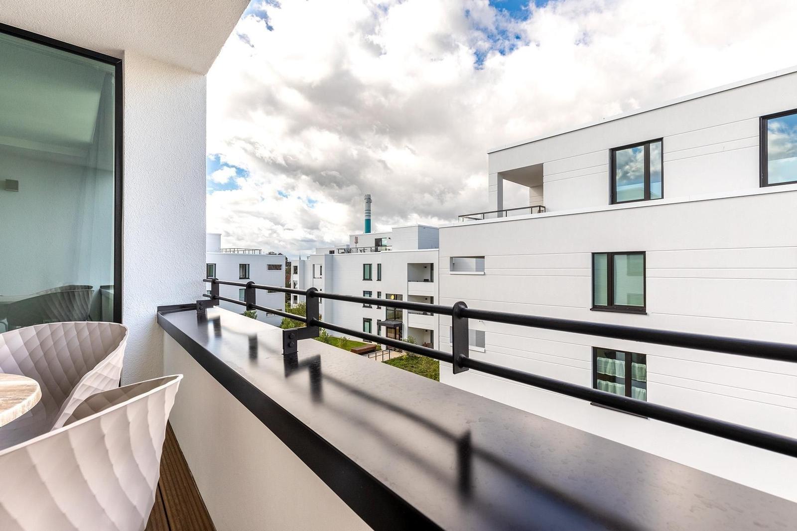 Terrasse mit Sitzgelegenheit und Blick auf moderne Gebäude.