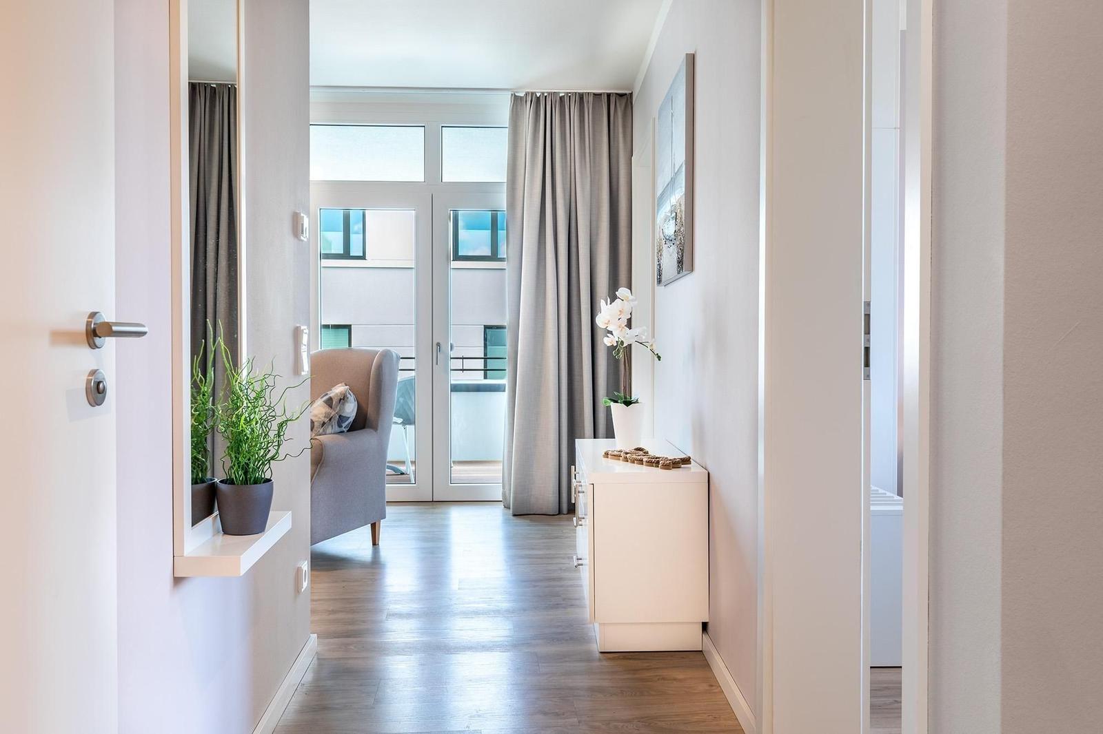 Halle mit Garderobe, Pflanzen und Blick auf Balkon mit Sitzgelegenheit.