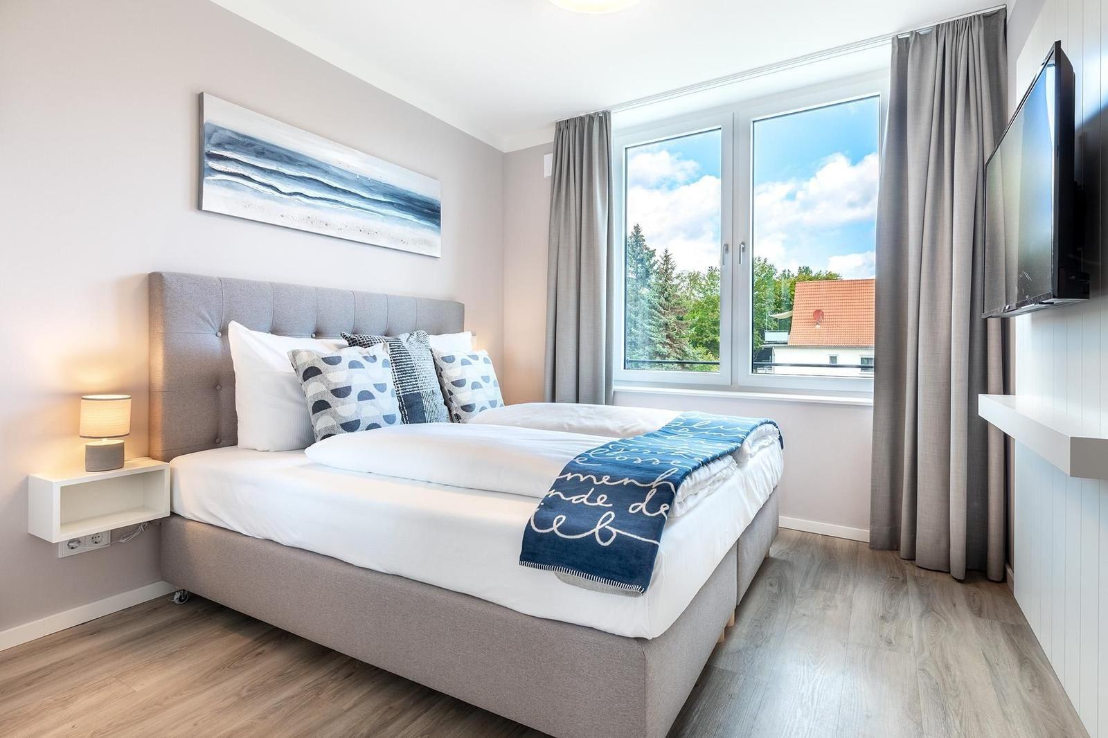 Schlafzimmer mit Bett, Fenster und TV.