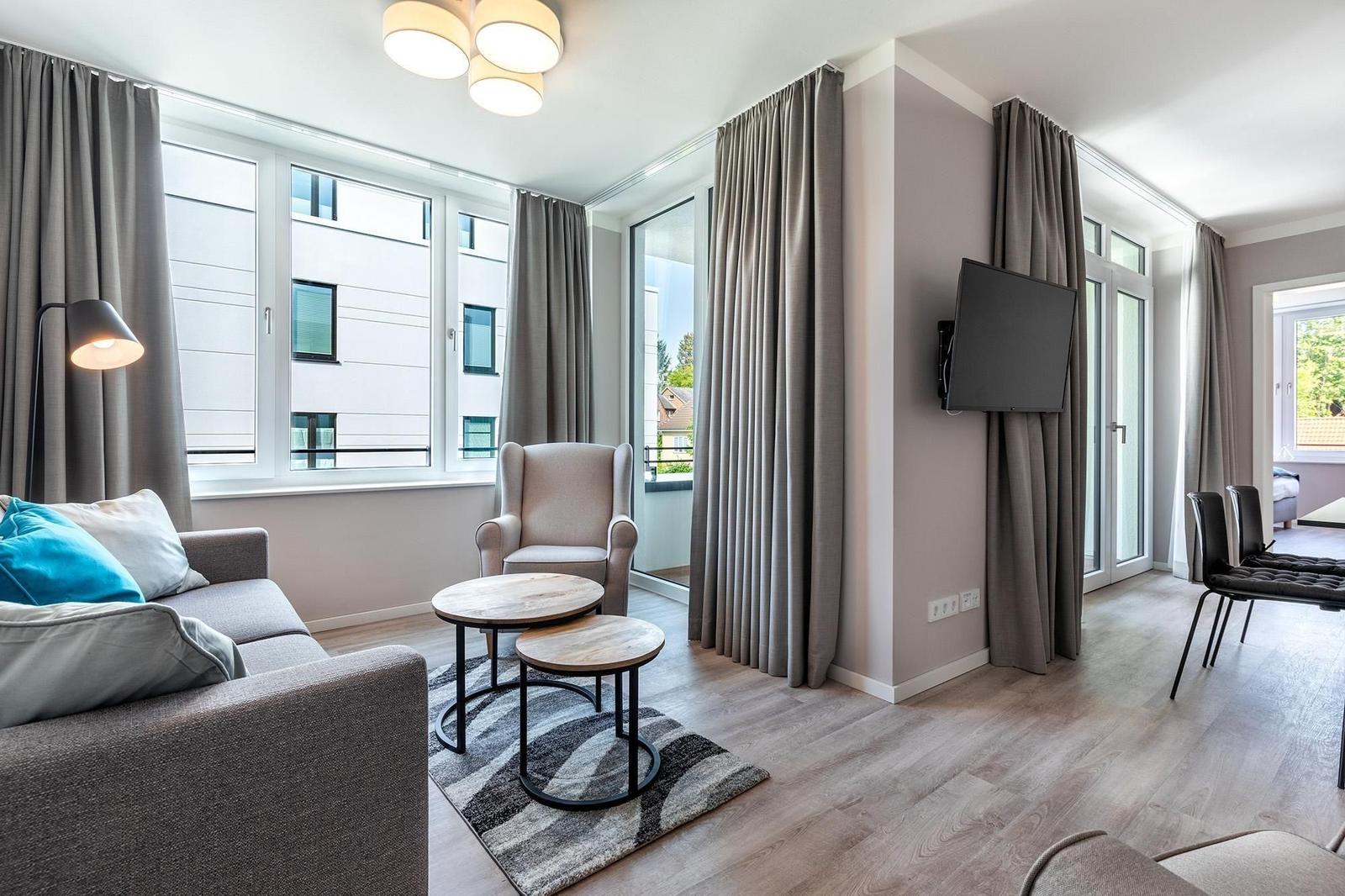 Wohnzimmer mit Sofa, Sessel und TV an der Wand.