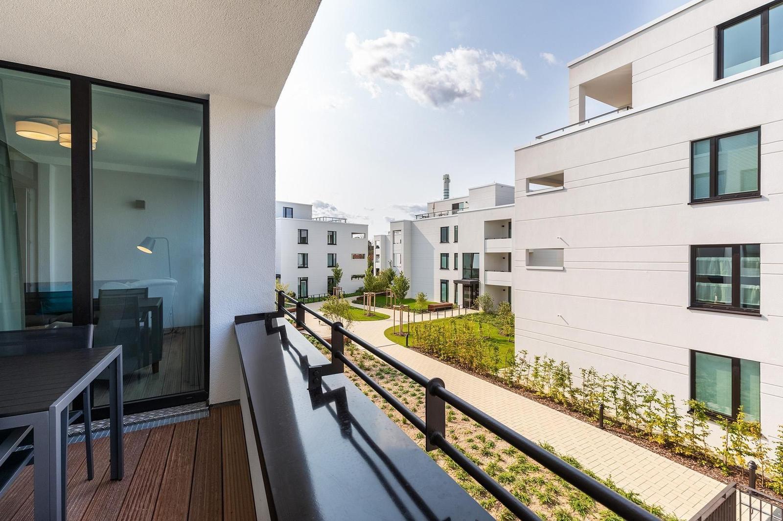 Terrasse mit Tisch und Blick auf moderne Wohnhäuser und Grünflächen.