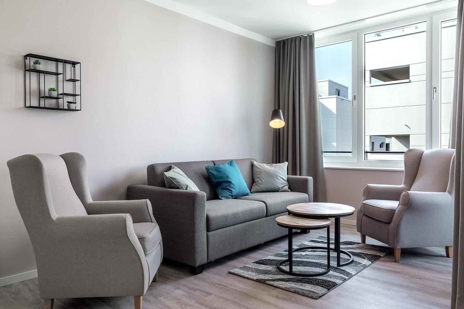 Wohnzimmer mit Sofa, zwei Sesseln und Fensterblick.