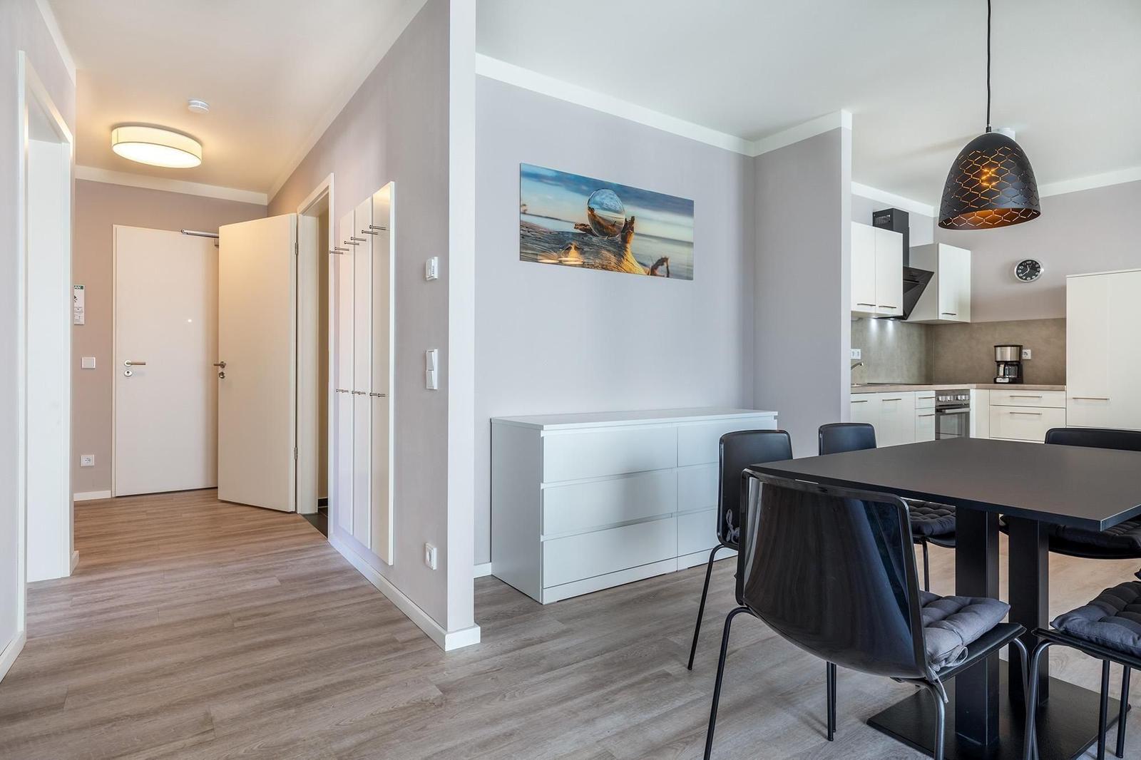 Essbereich mit Tisch und Stühlen, weiße Schränke und Wandbild.