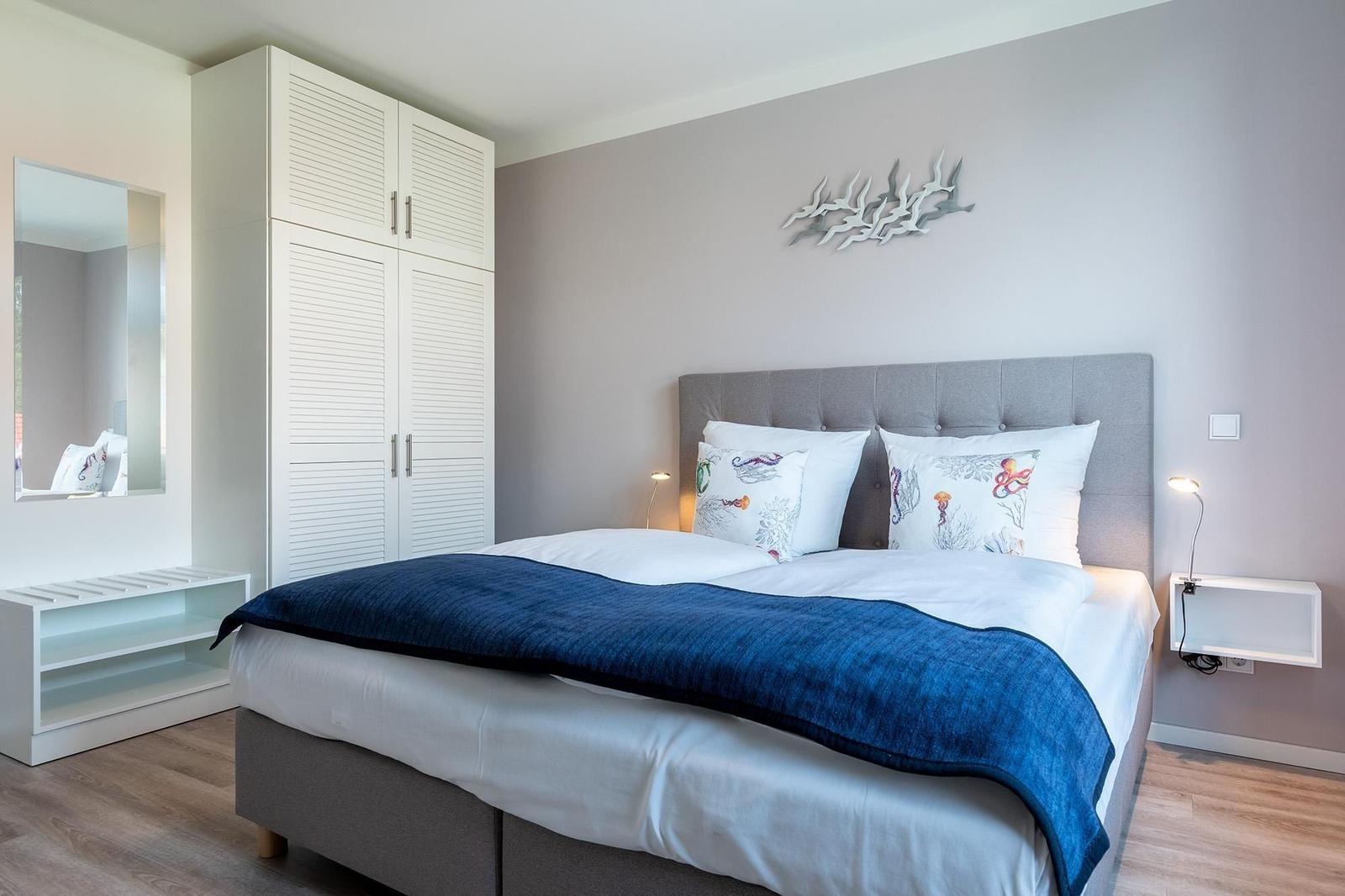 Schlafzimmer mit Bett, Kleiderschrank und Wanddekoration.