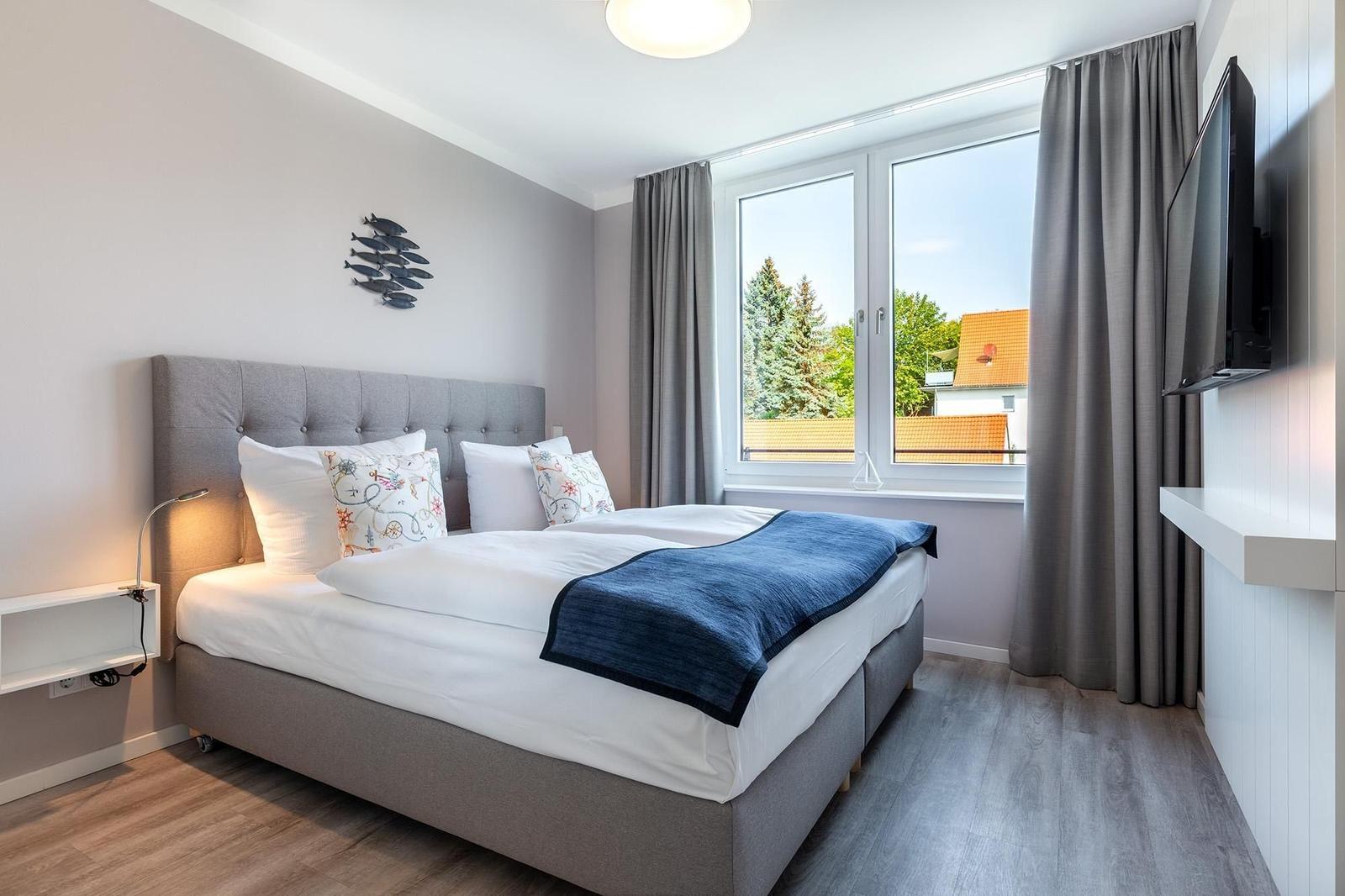 Schlafzimmer mit Bett, Fenster und TV.