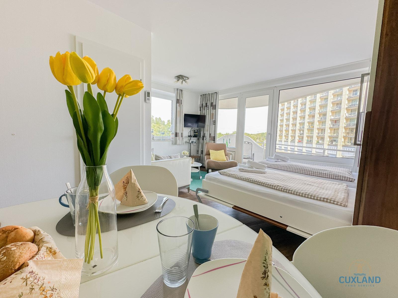 Tisch mit Tulpen, Bett und Wohnbereich mit Blick auf Gebäude.
