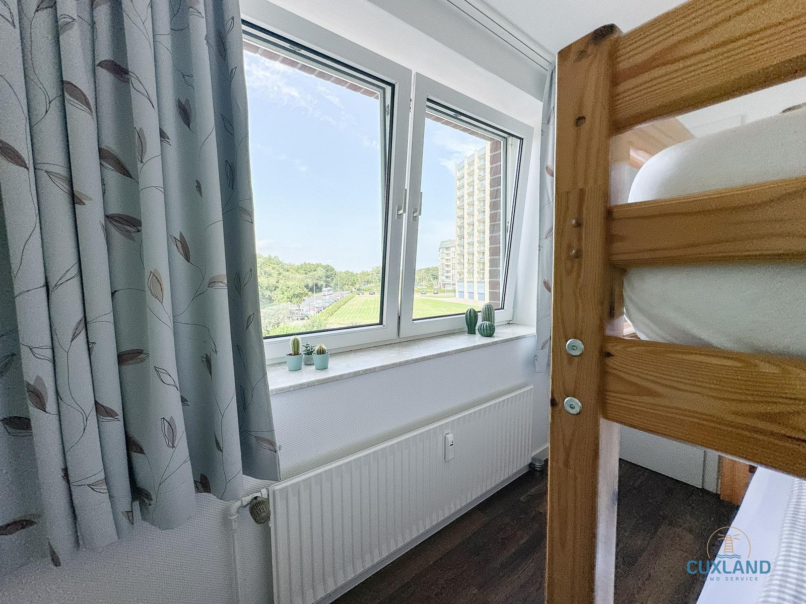 Ein Schlafzimmer mit einem Bett und einem Fenster mit Blick auf eine Grünfläche.