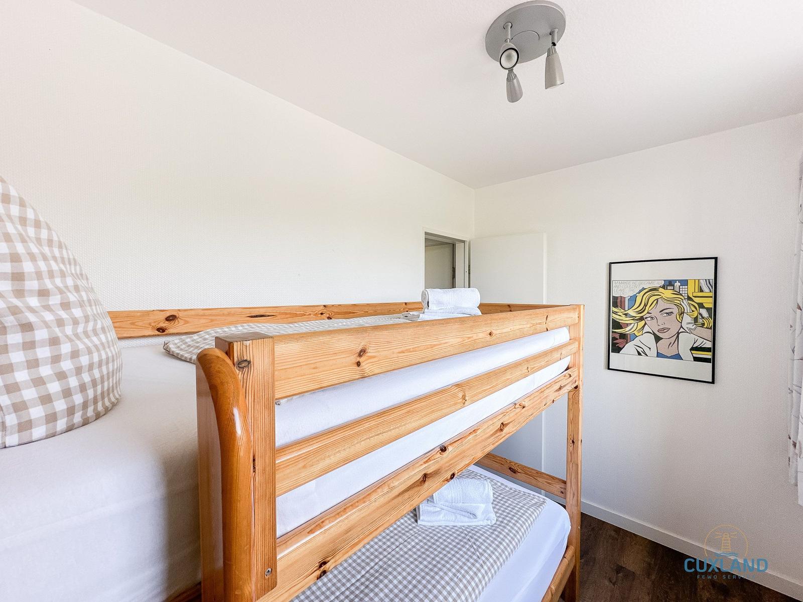 Doppelstockbett mit Holzgestell und Bettwäsche. Wandbild und Deckenleuchte.