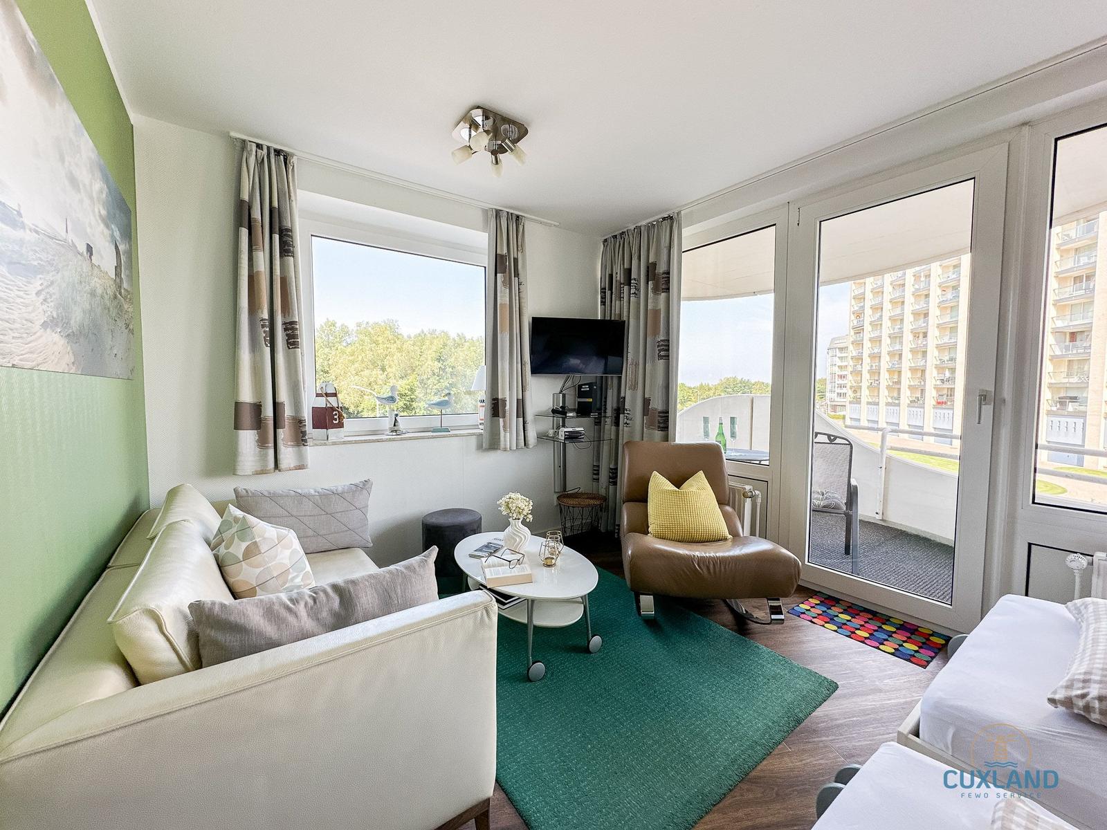 Wohnzimmer mit Sofa, Sessel und Balkonansicht