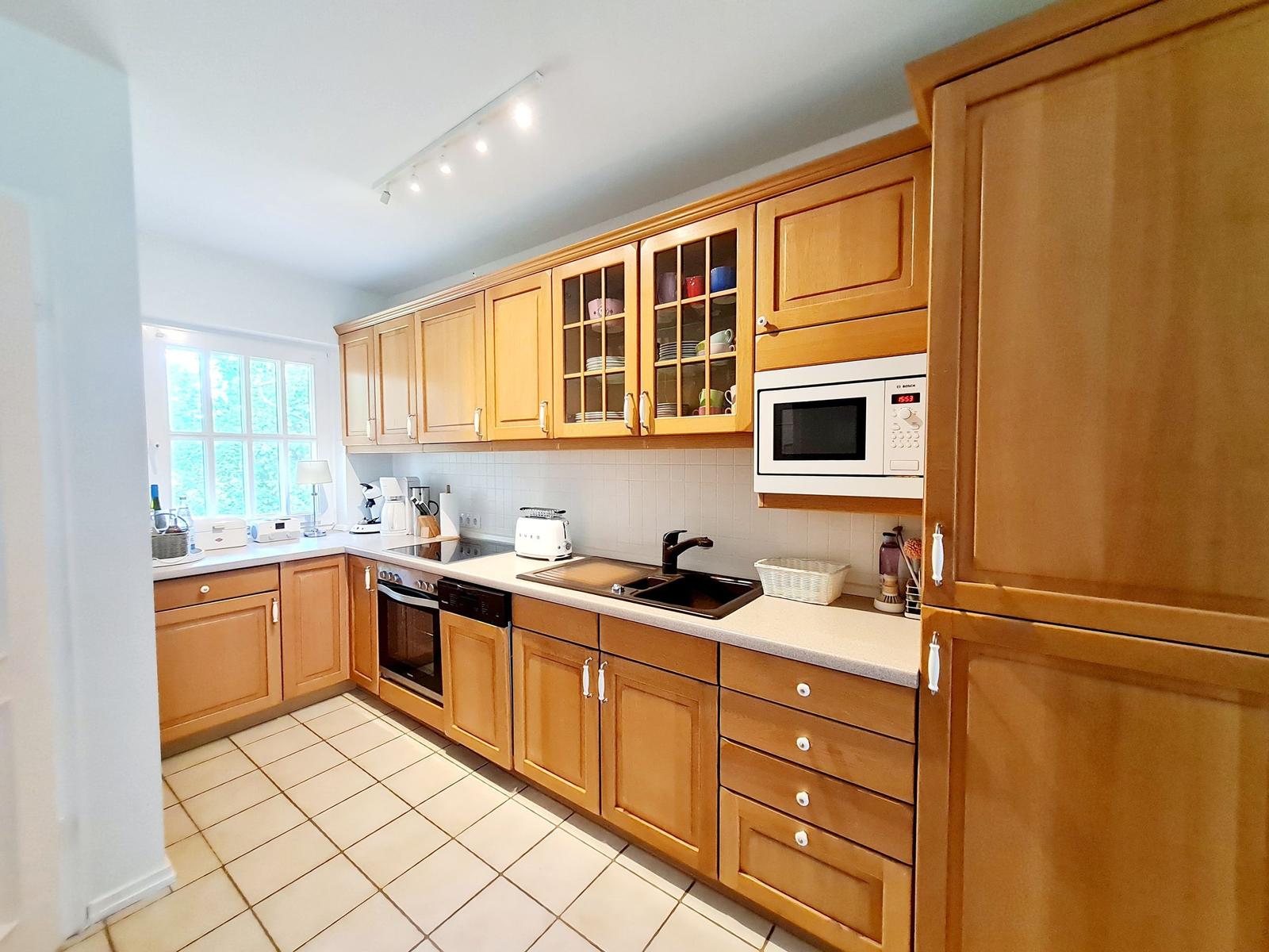 Küche mit Holzschränken, Spüle und Mikrowelle