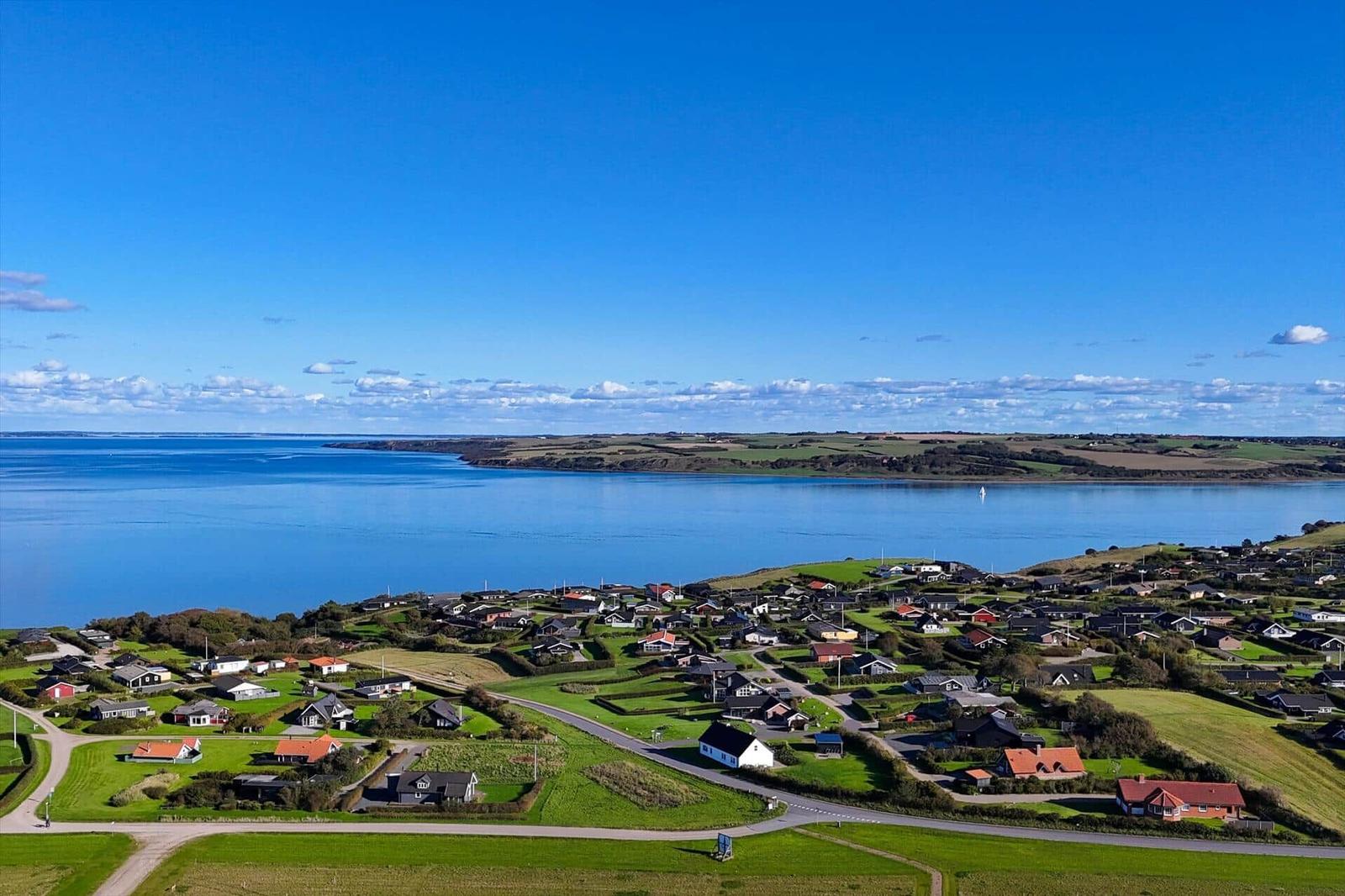 Panoramablick auf Küstenort mit Häusern und blauem Meer unter klarem Himmel.