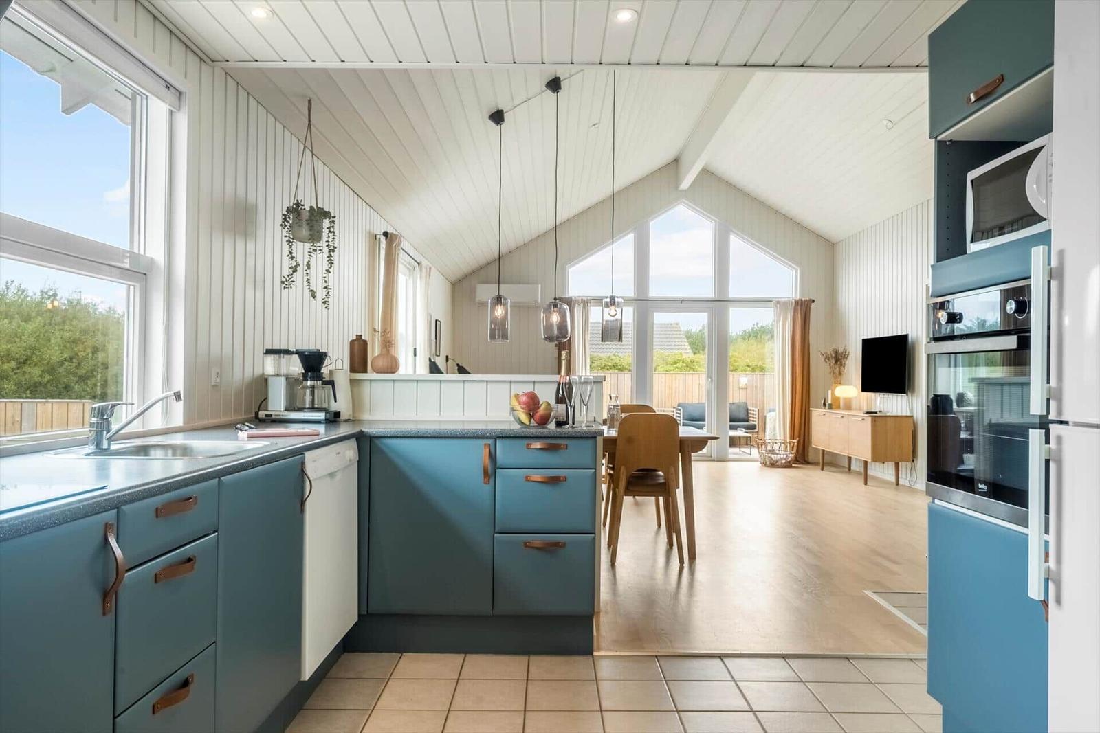 Küche mit blauen Schränken und Essbereich mit Holztisch.