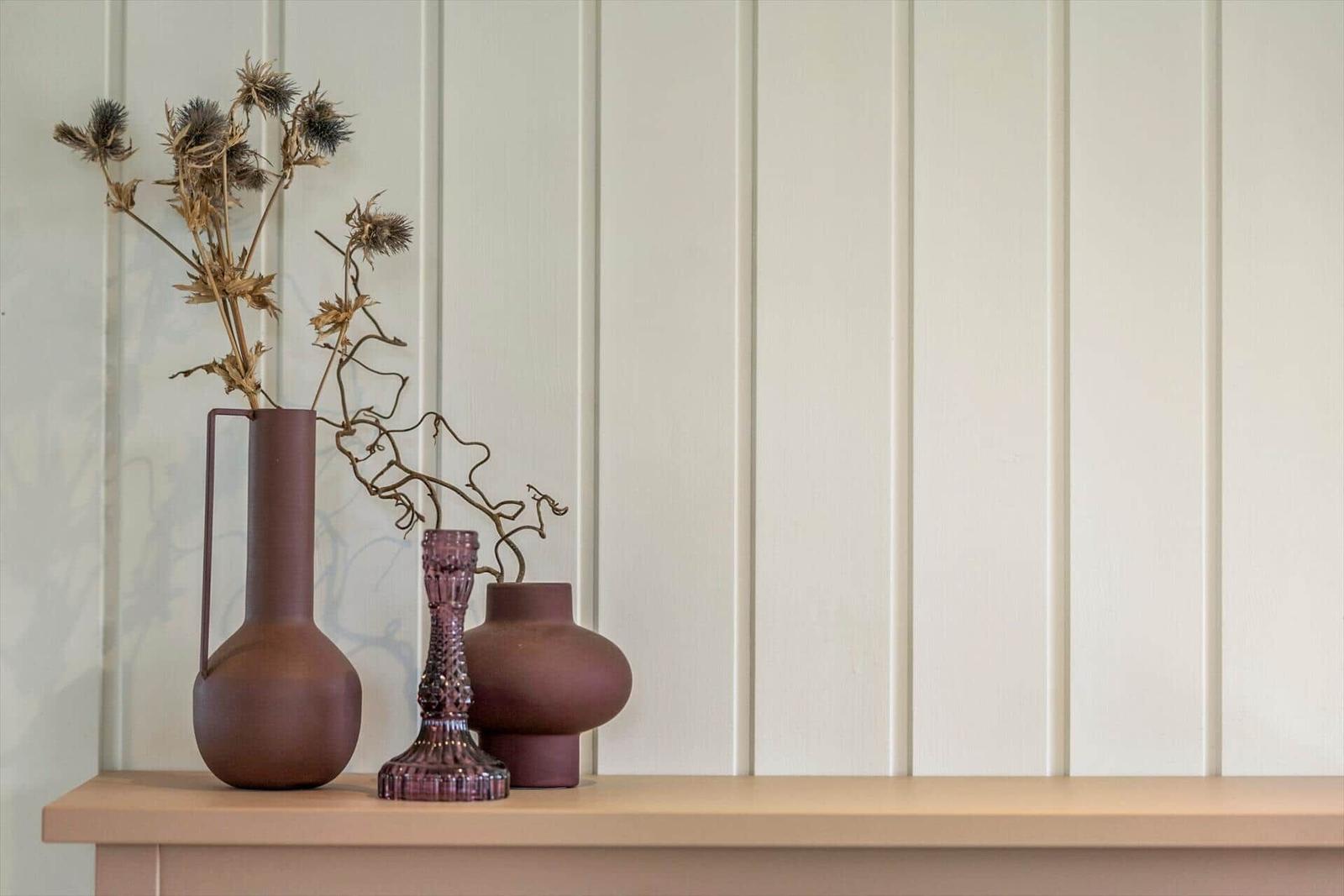 Drei Vasen mit getrockneten Pflanzen auf einer Holzoberfläche.