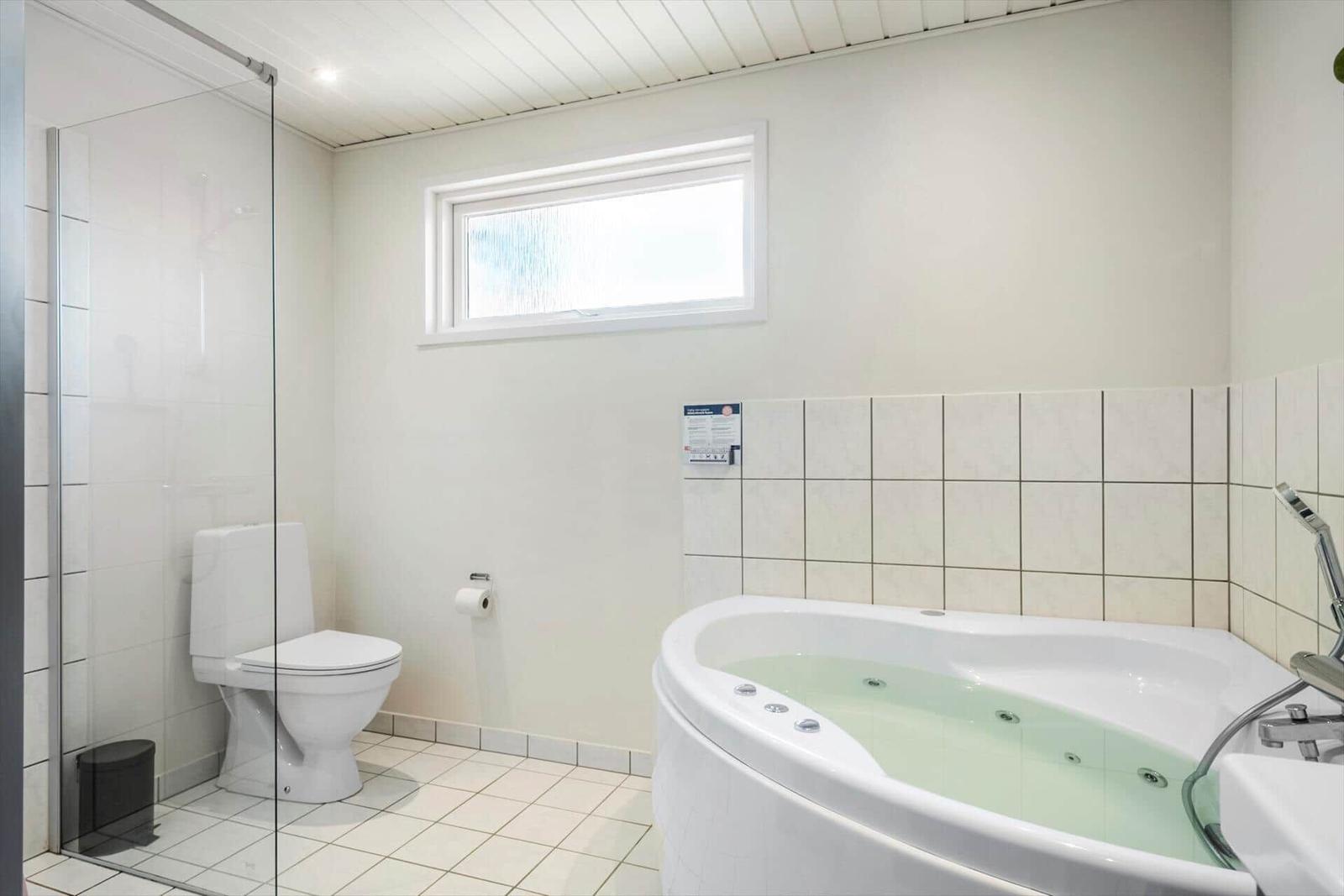 Bad mit Whirlpool, Toilette und Dusche hinter Glas