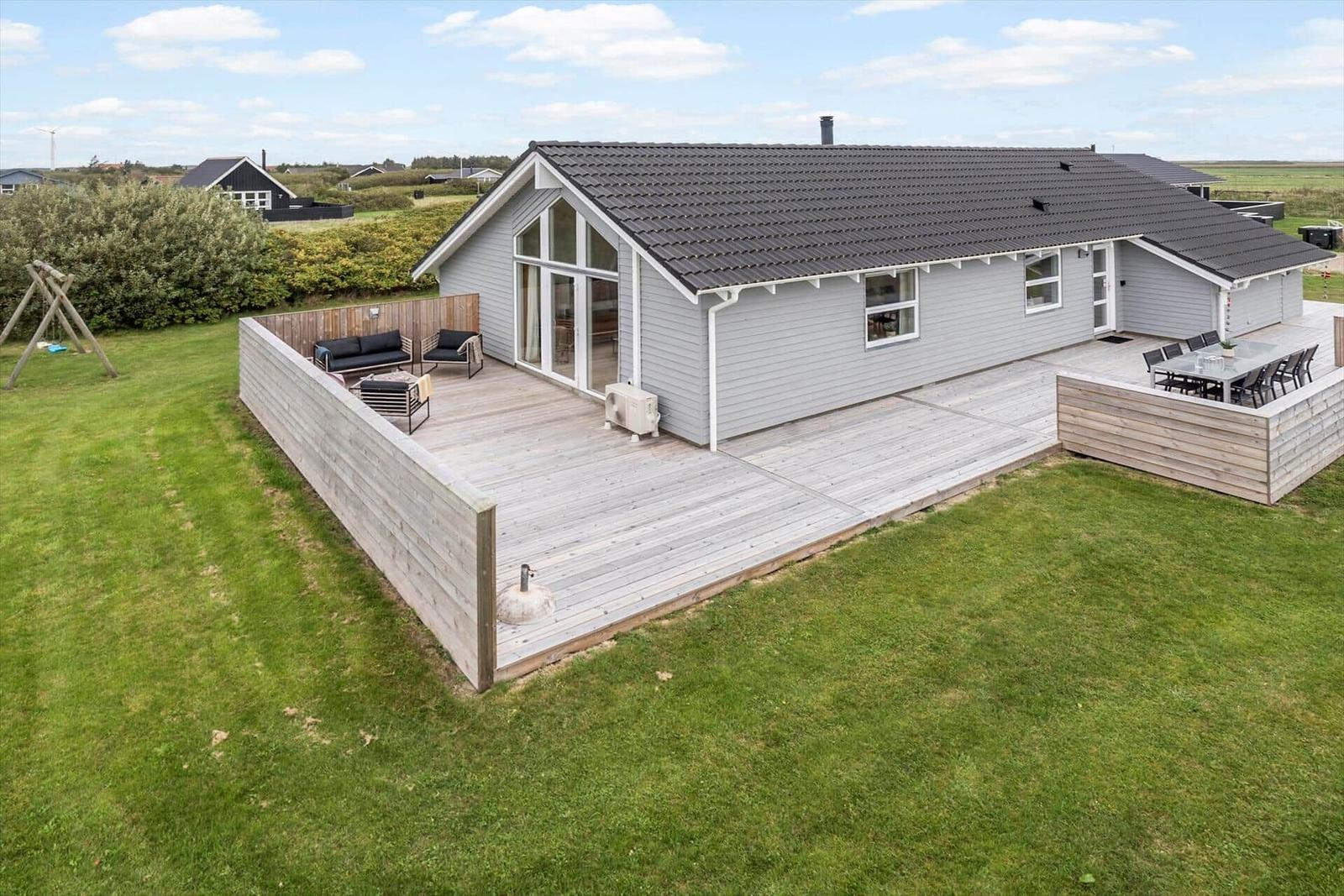 Moderne Ferienhaus mit großer Terrasse, Garten und Außensitzgelegenheiten.