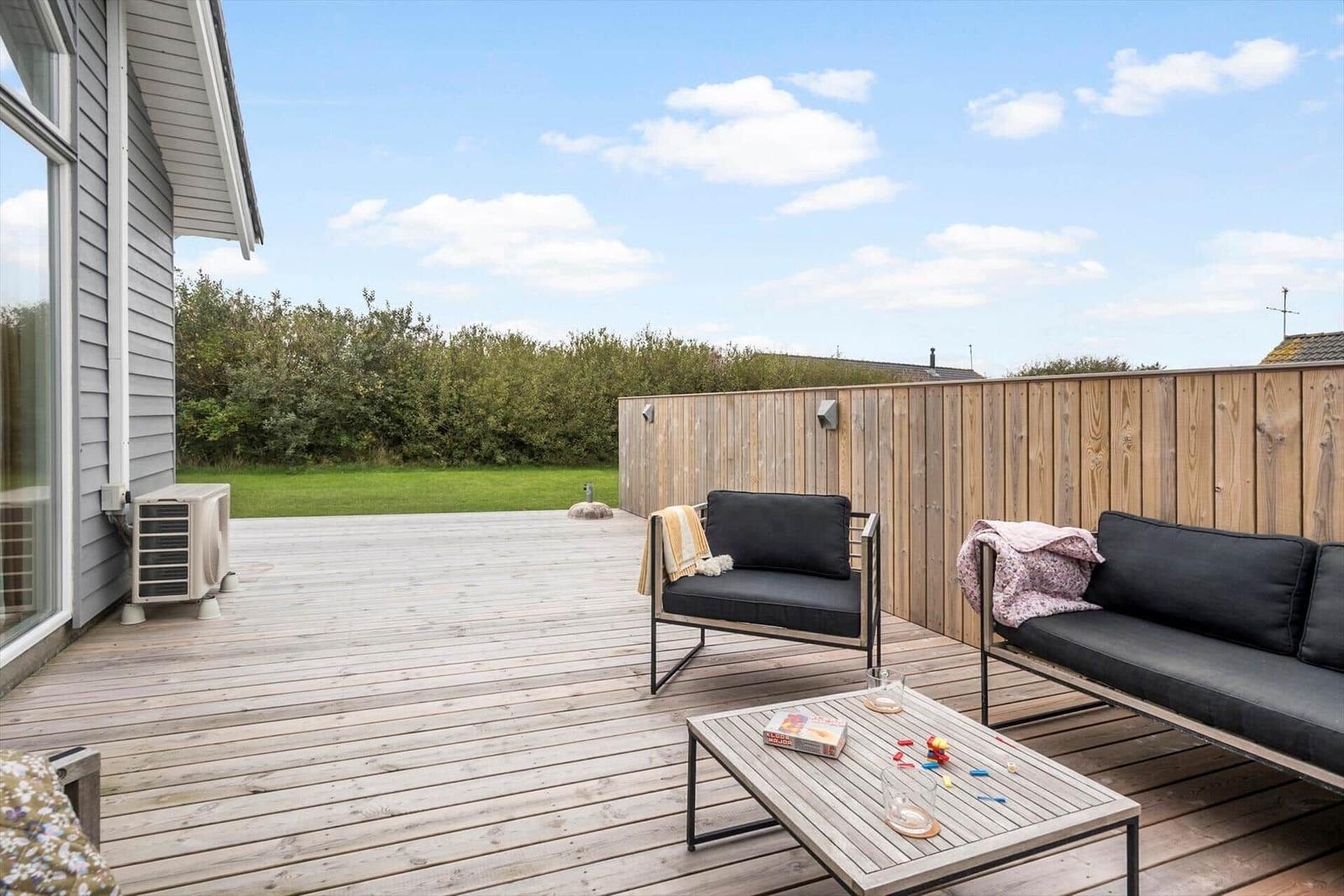 Terrasse mit Sitzgruppe, Tisch und Blick auf Grünfläche.