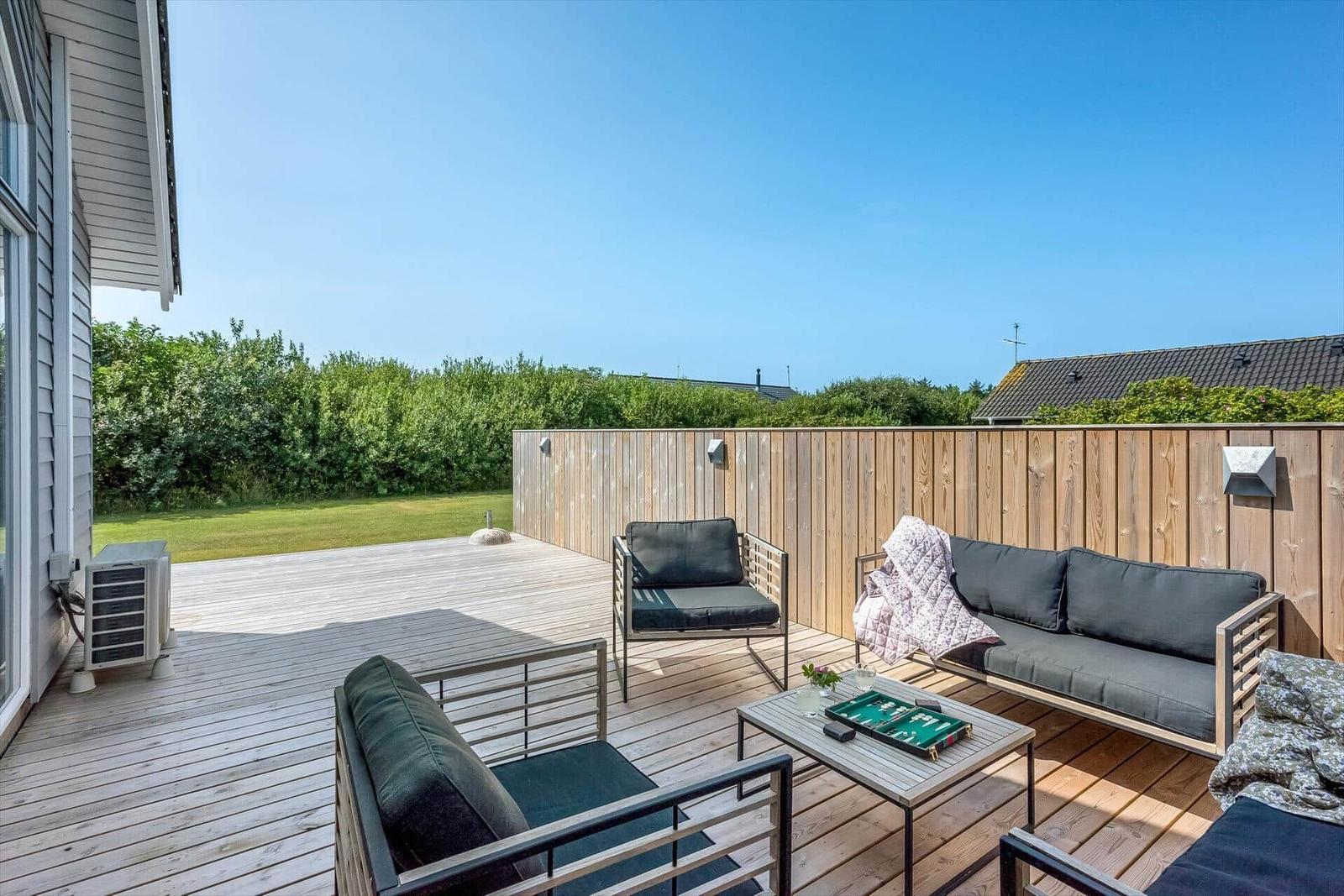 Terrasse mit Sitzgruppe, Tisch und Blick auf Grünfläche.