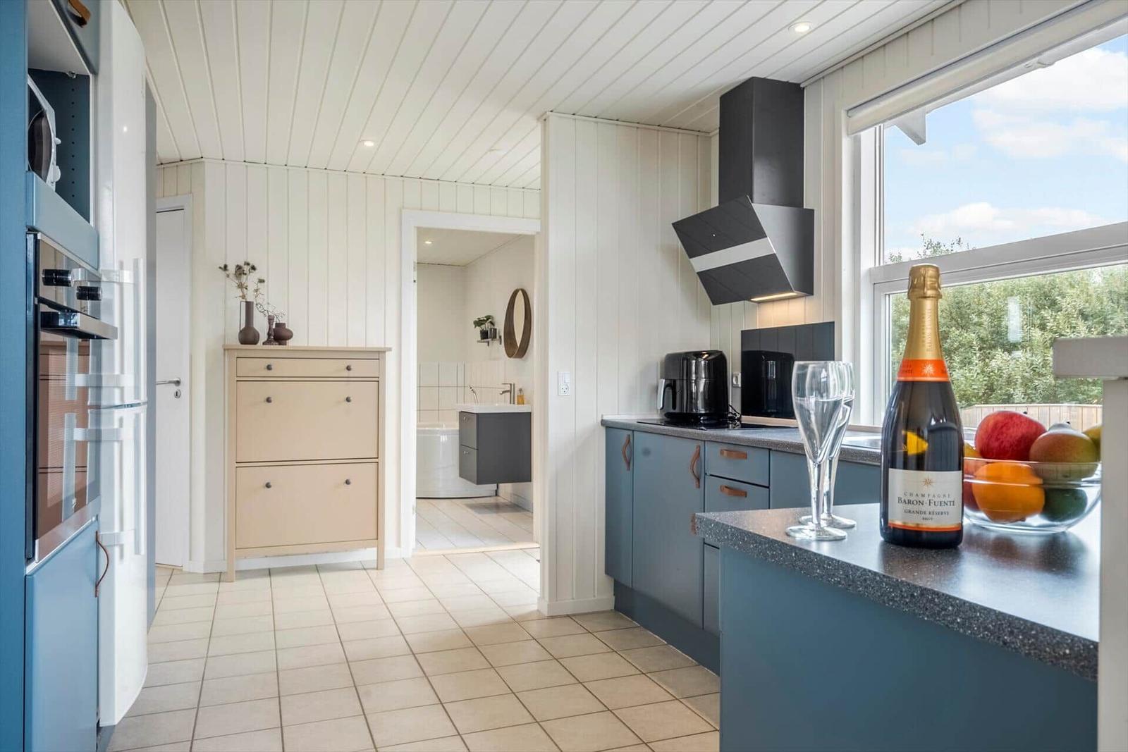 Küche mit Blick auf Bad. Auf der Arbeitsplatte steht eine Champagnerflasche.