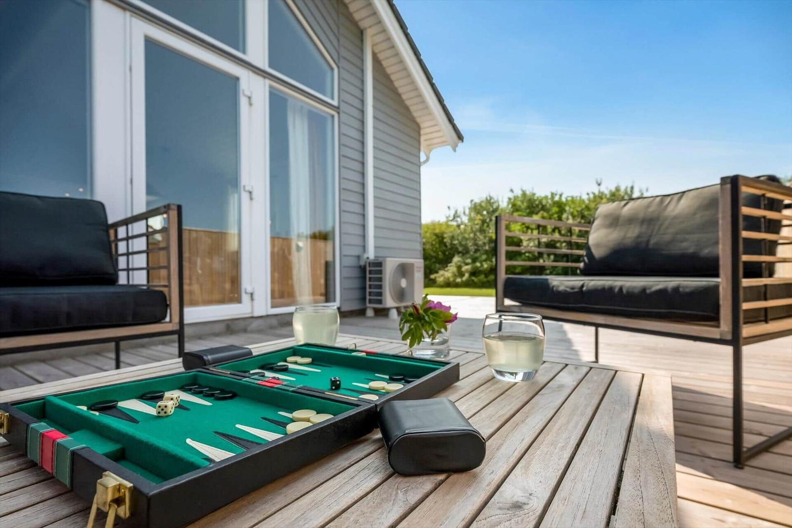 Backgammon auf Terrasse mit Sitzgelegenheiten und Blick auf Haus.