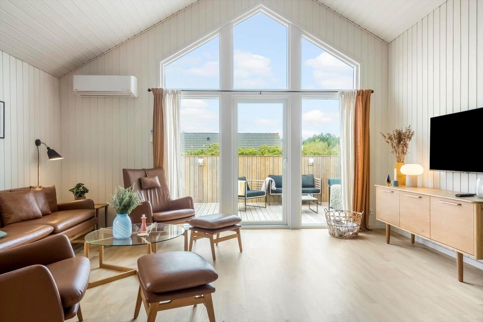 Wohnzimmer mit braunen Ledermöbeln und großem Fenster zur Terrasse.