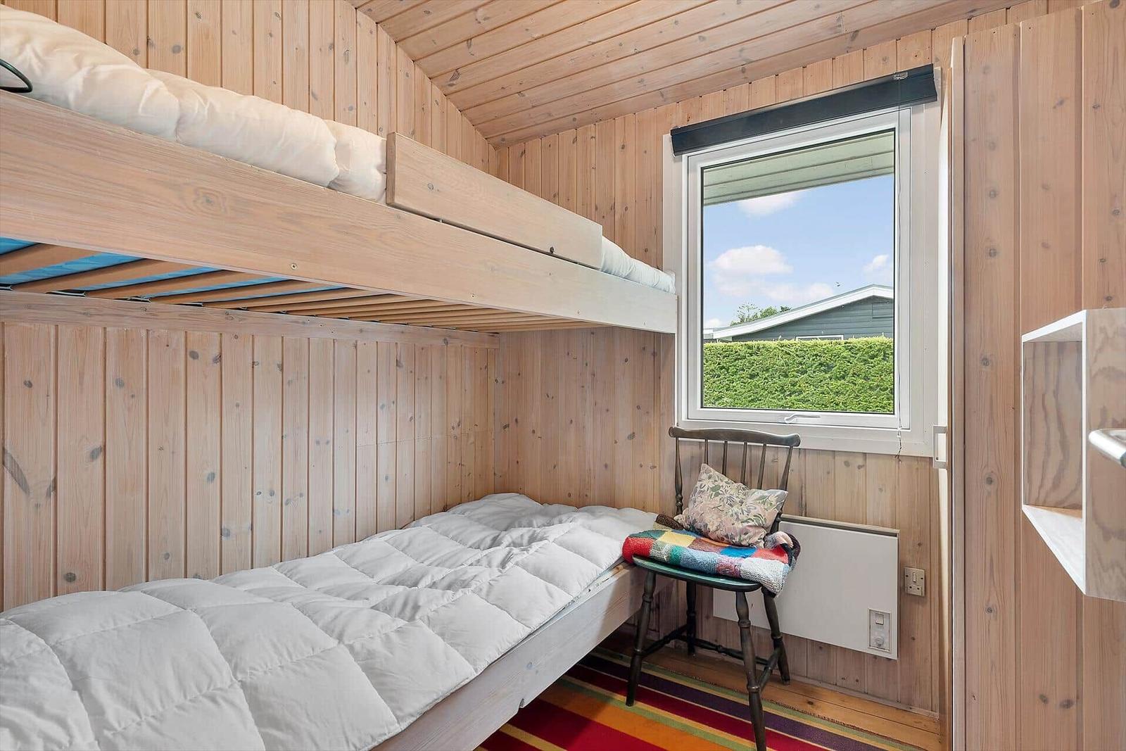 Zimmer mit Doppelstockbett, Fenster und Stuhl