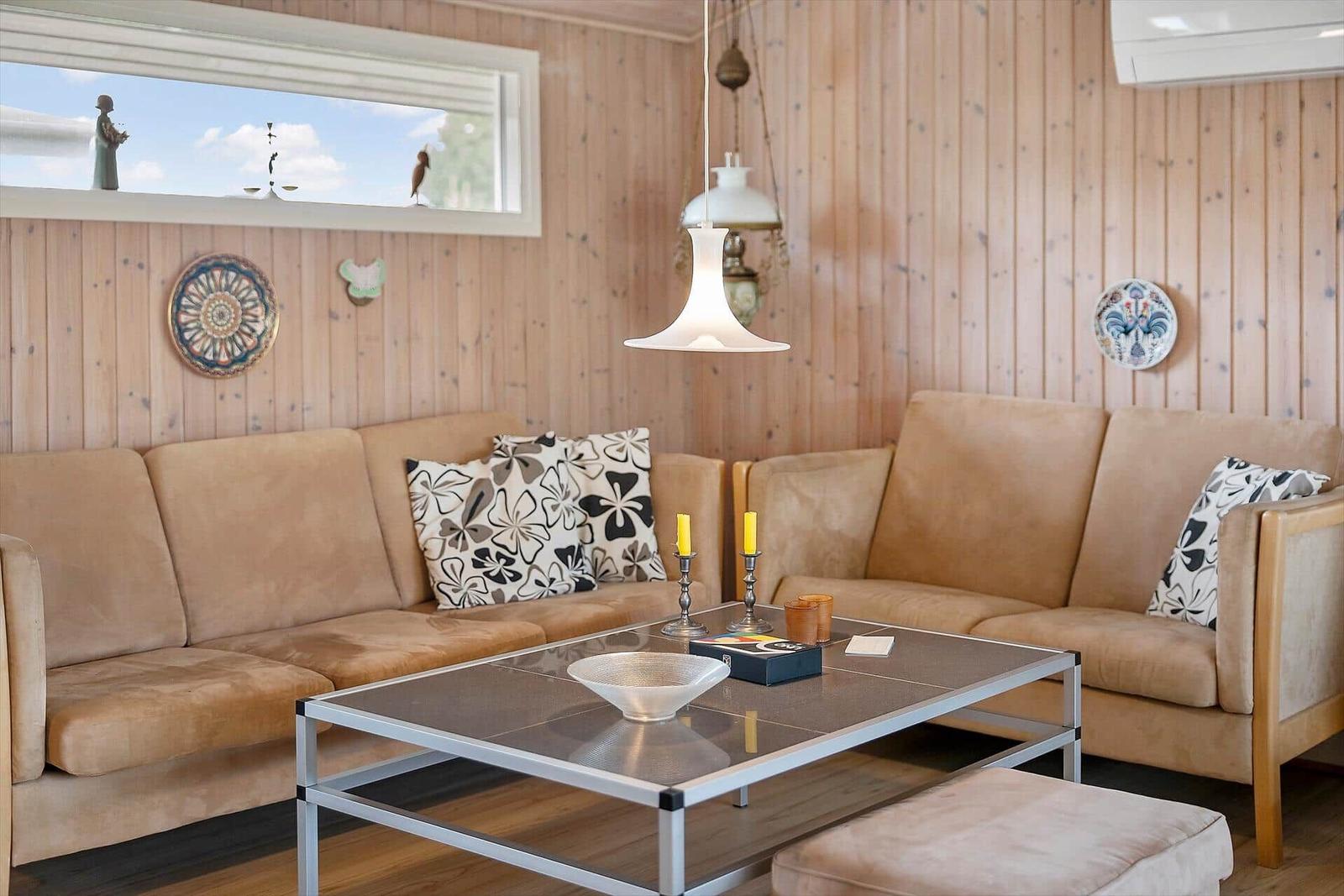 Zwei Sofas mit Kissen, Glas-Tisch und Holzwand im Wohnzimmer.