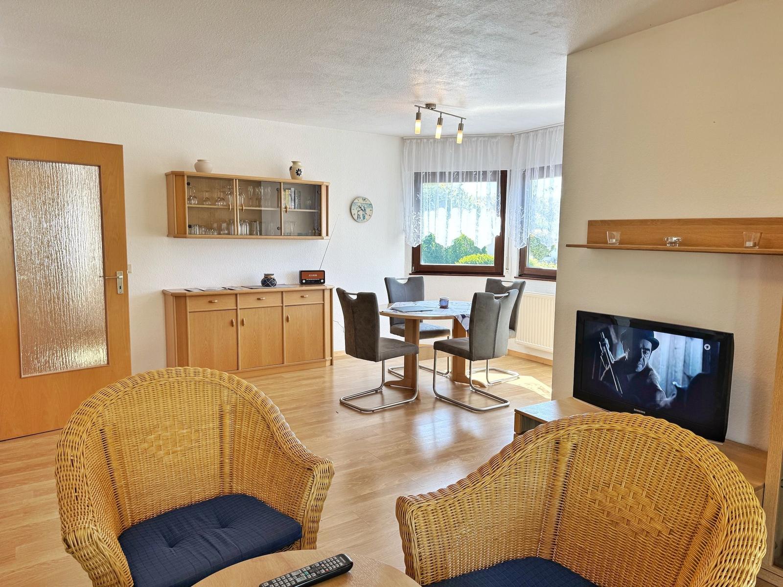 Wohnzimmer mit Essbereich, Fernseher und Holzmöbel.