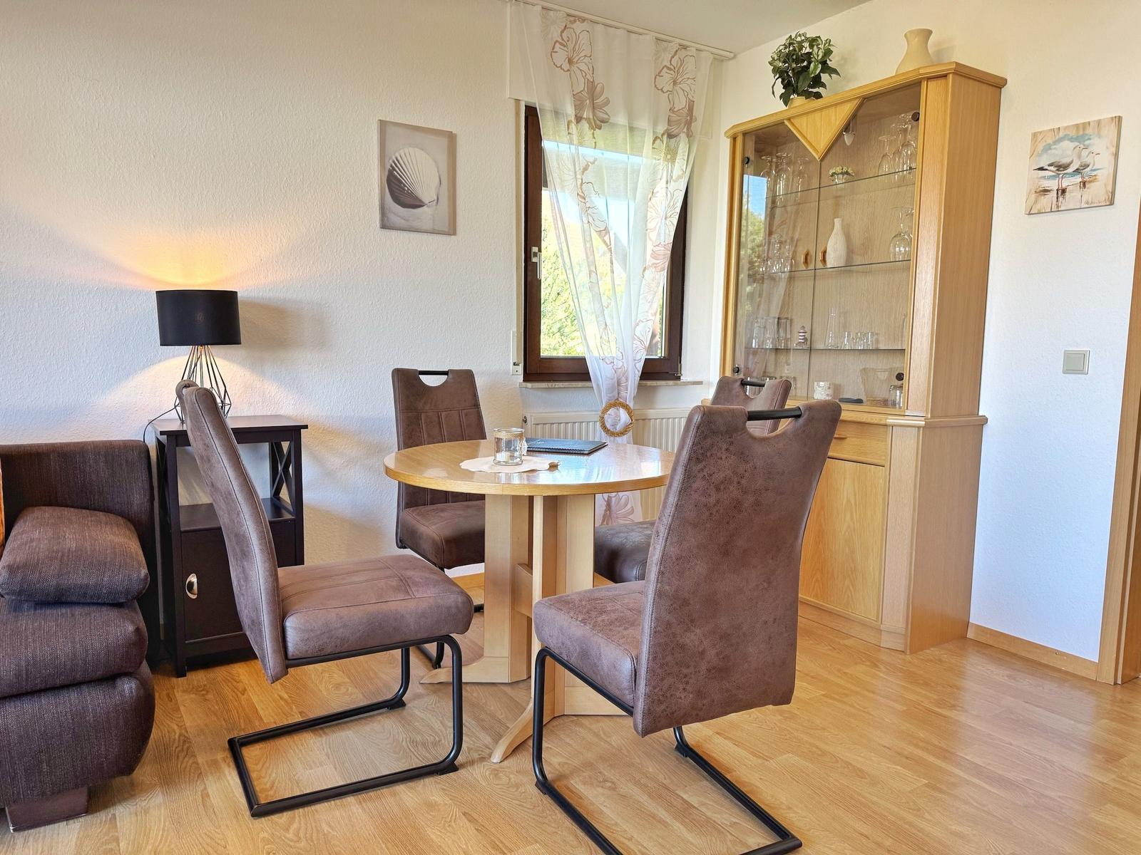 Essbereich mit runden Tisch, vier Stühlen und Glasvitrine.