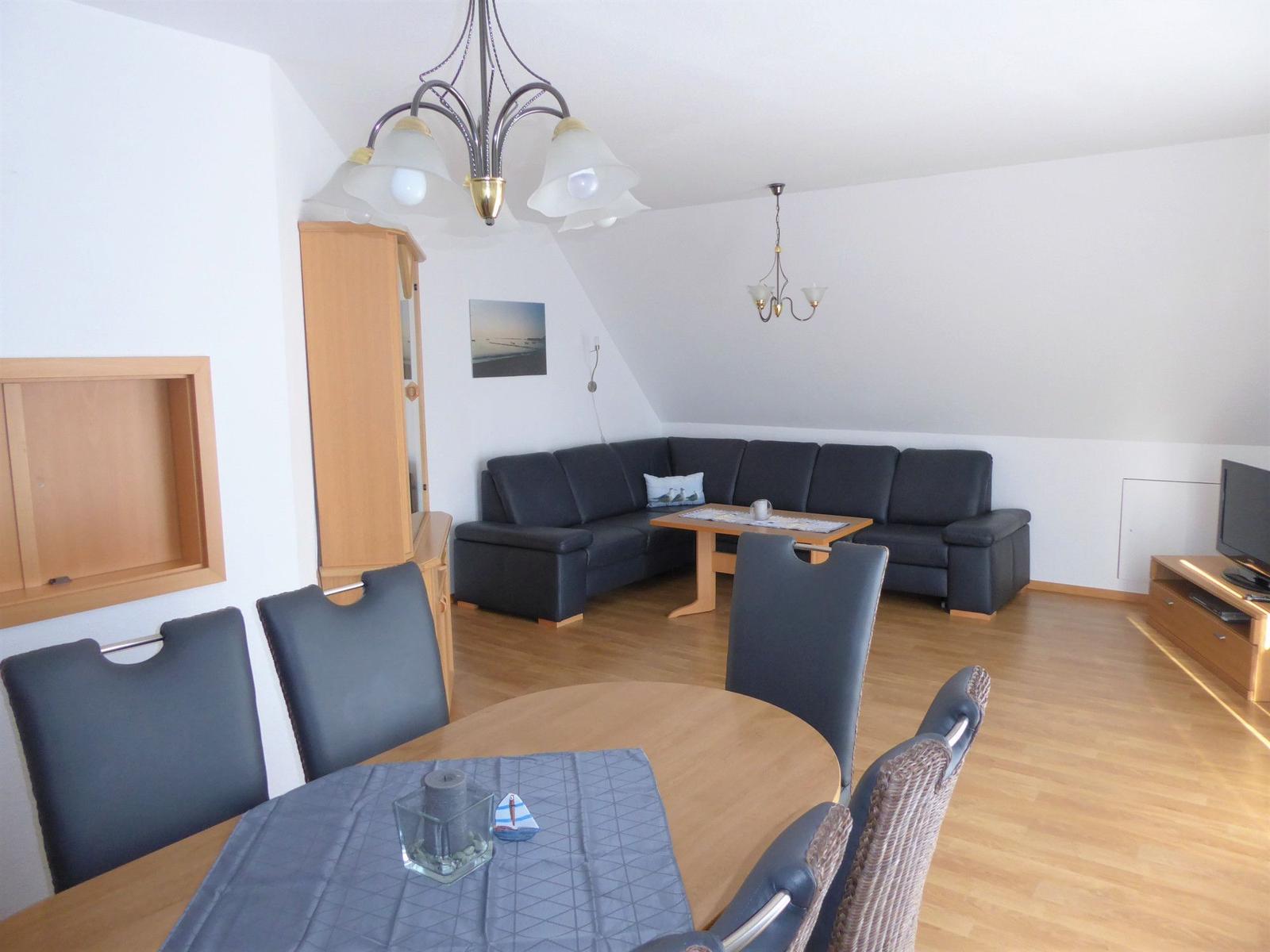 Wohn- und Essbereich mit Sofa, Esstisch und Holzboden.