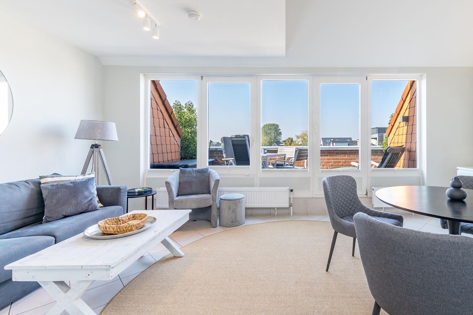 Wohn- und Essbereich mit großem Fensterblick auf Balkon und Dächer.