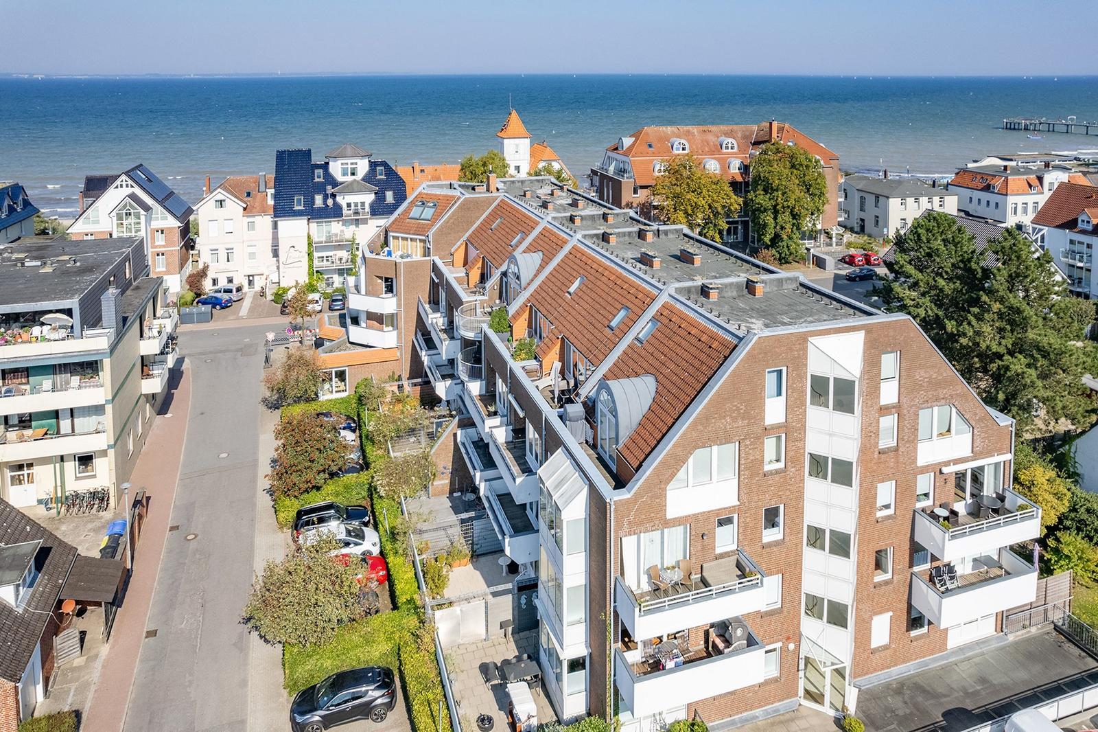 Meerblick auf Wohnhäuser mit Balkonen und gepflegten Gärten