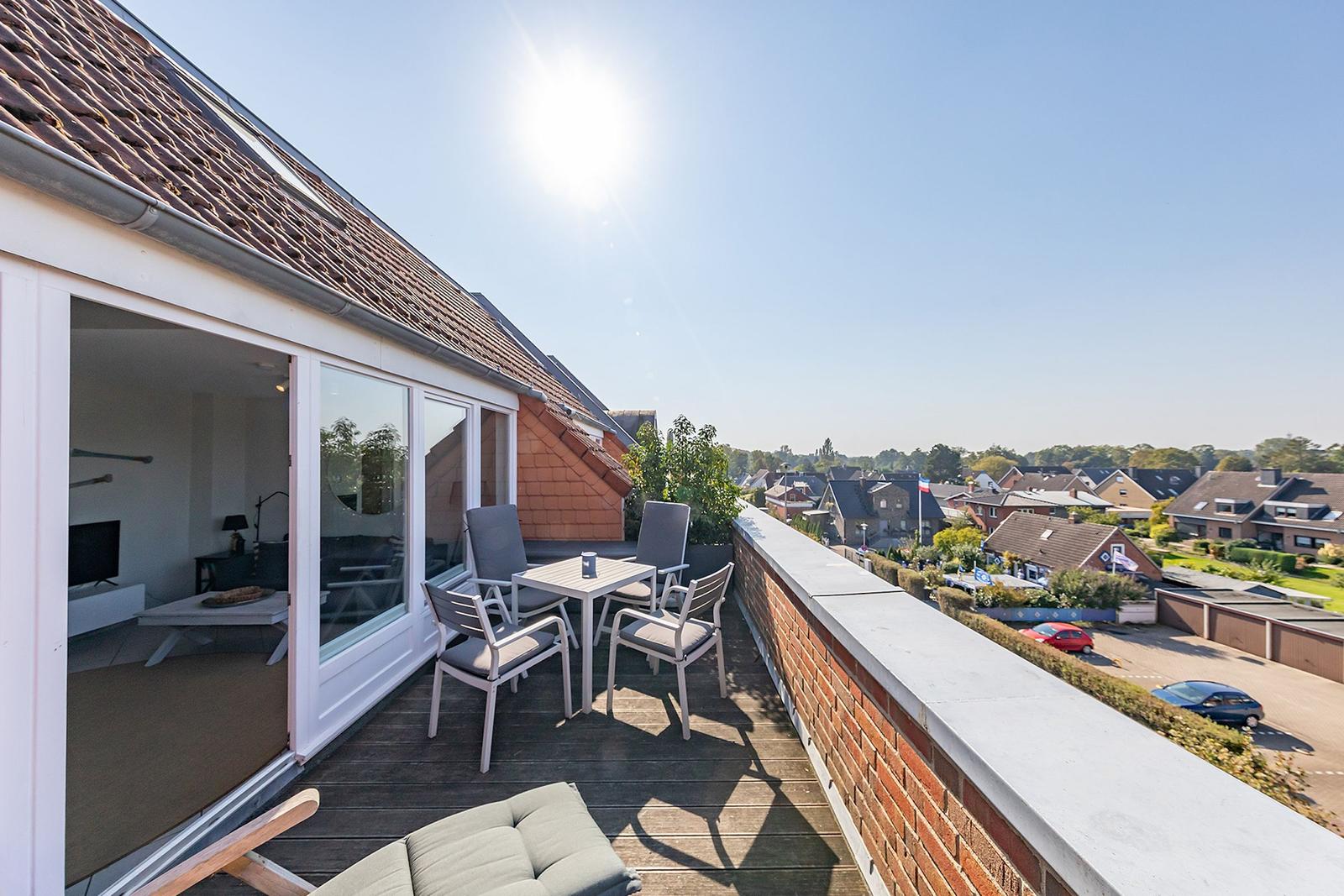 Terrasse mit Sitzgruppe und Blick auf Wohngebiet unter blauem Himmel