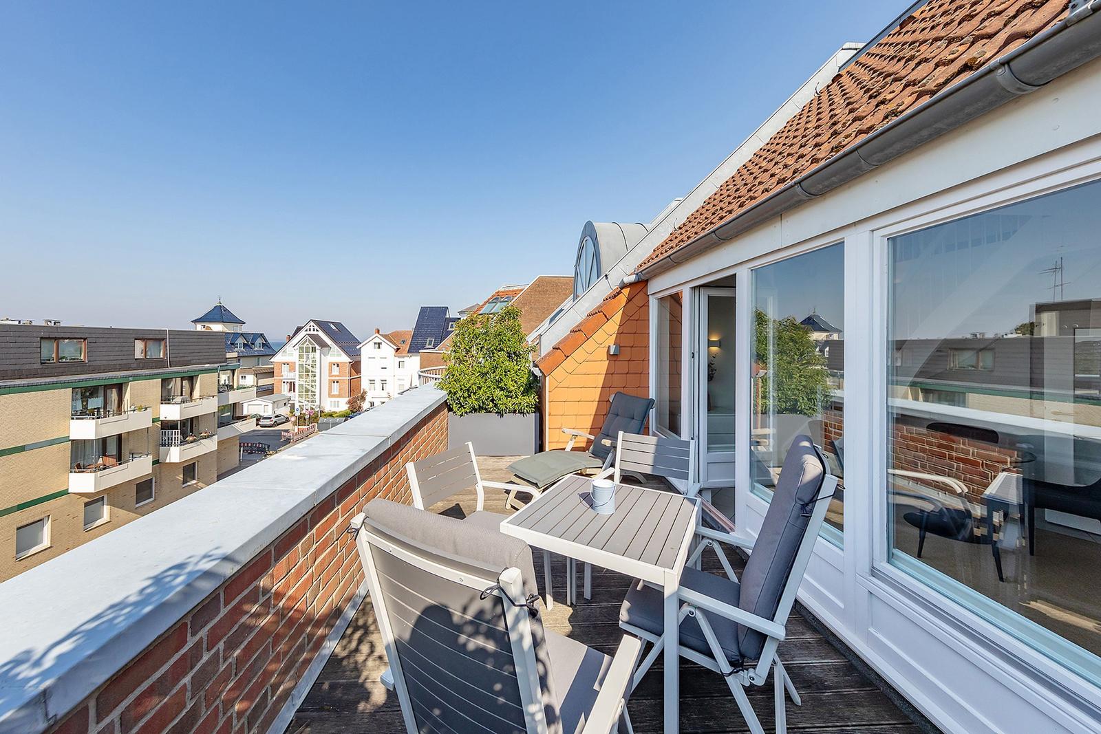 Terrasse mit Tisch und Stühlen, Blick auf Wohnhäuser und Dächer.