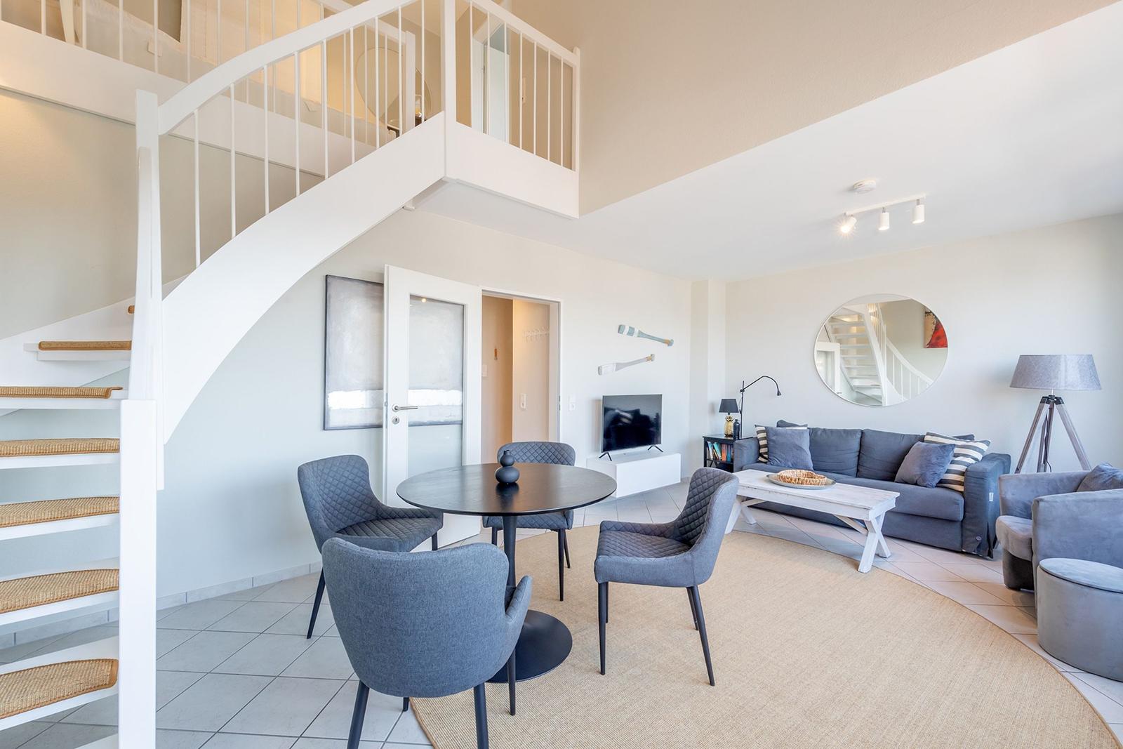 Wohnbereich mit Essbereich, Sofa und Treppe zur oberen Etage.