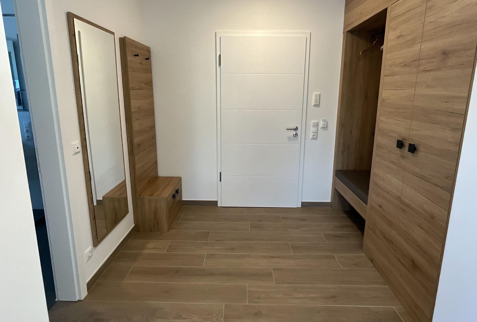 Eingangsbereich mit Spiegel, Kleiderschrank und Tür.