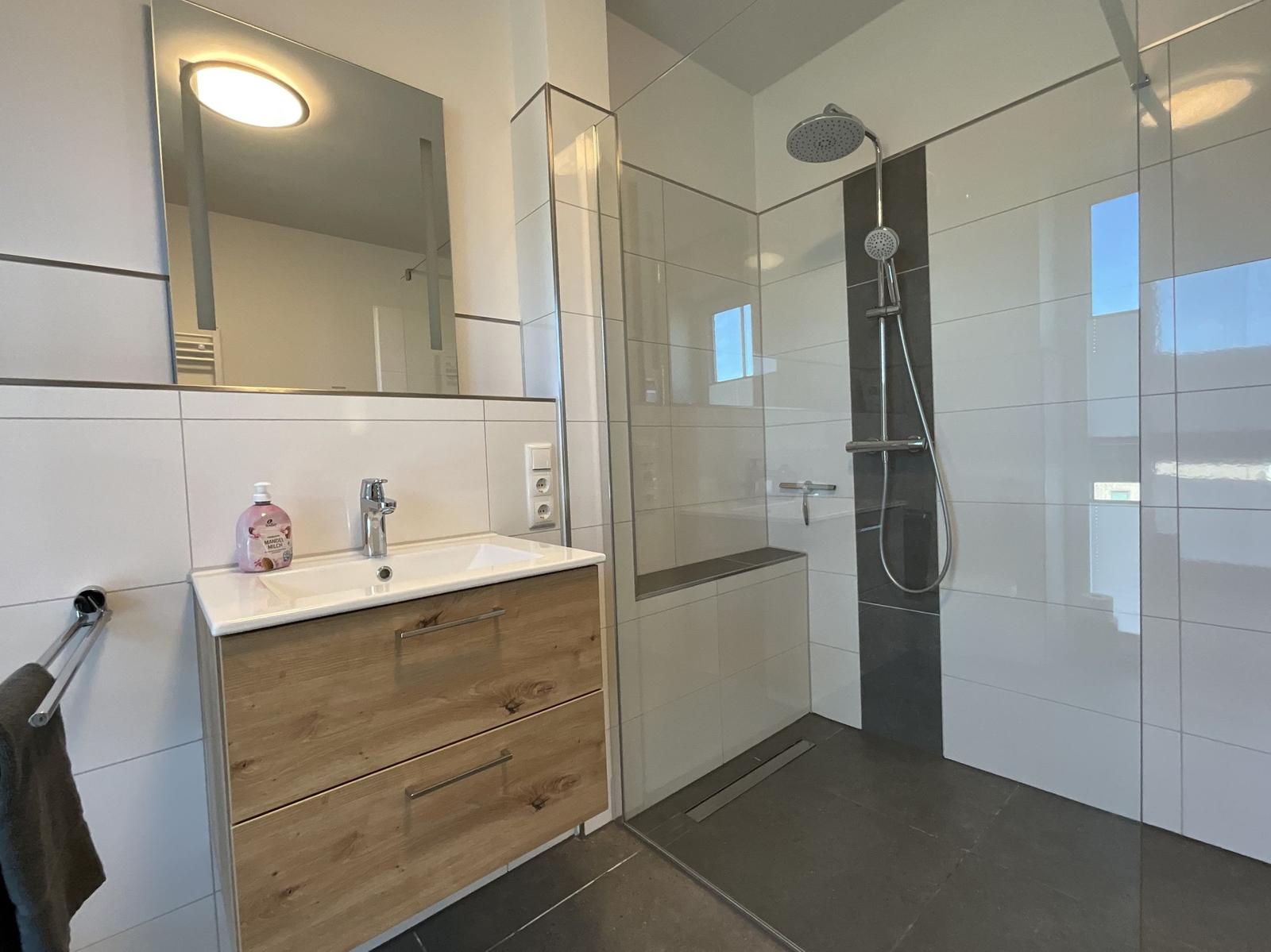 Badezimmer mit Dusche, Waschbecken und Spiegel