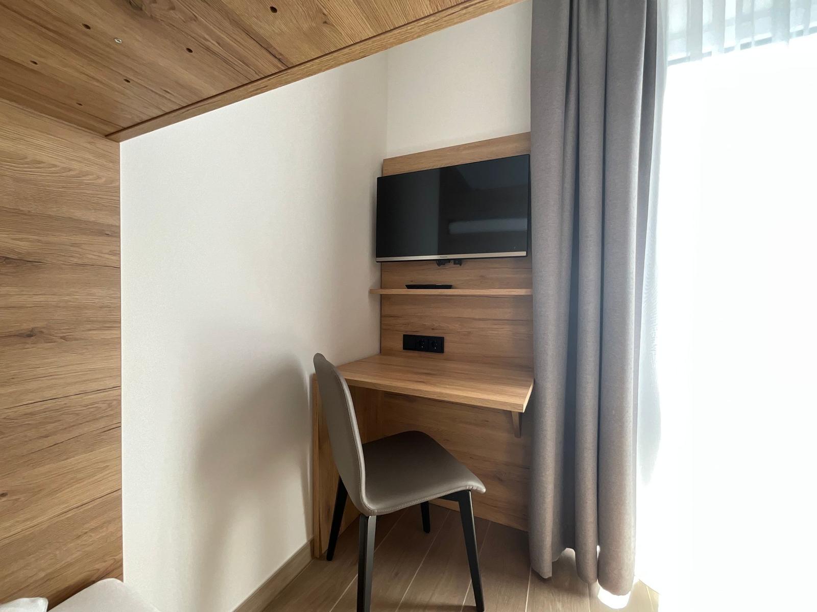 Schreibtisch mit Fernseher und Stuhl an Wand