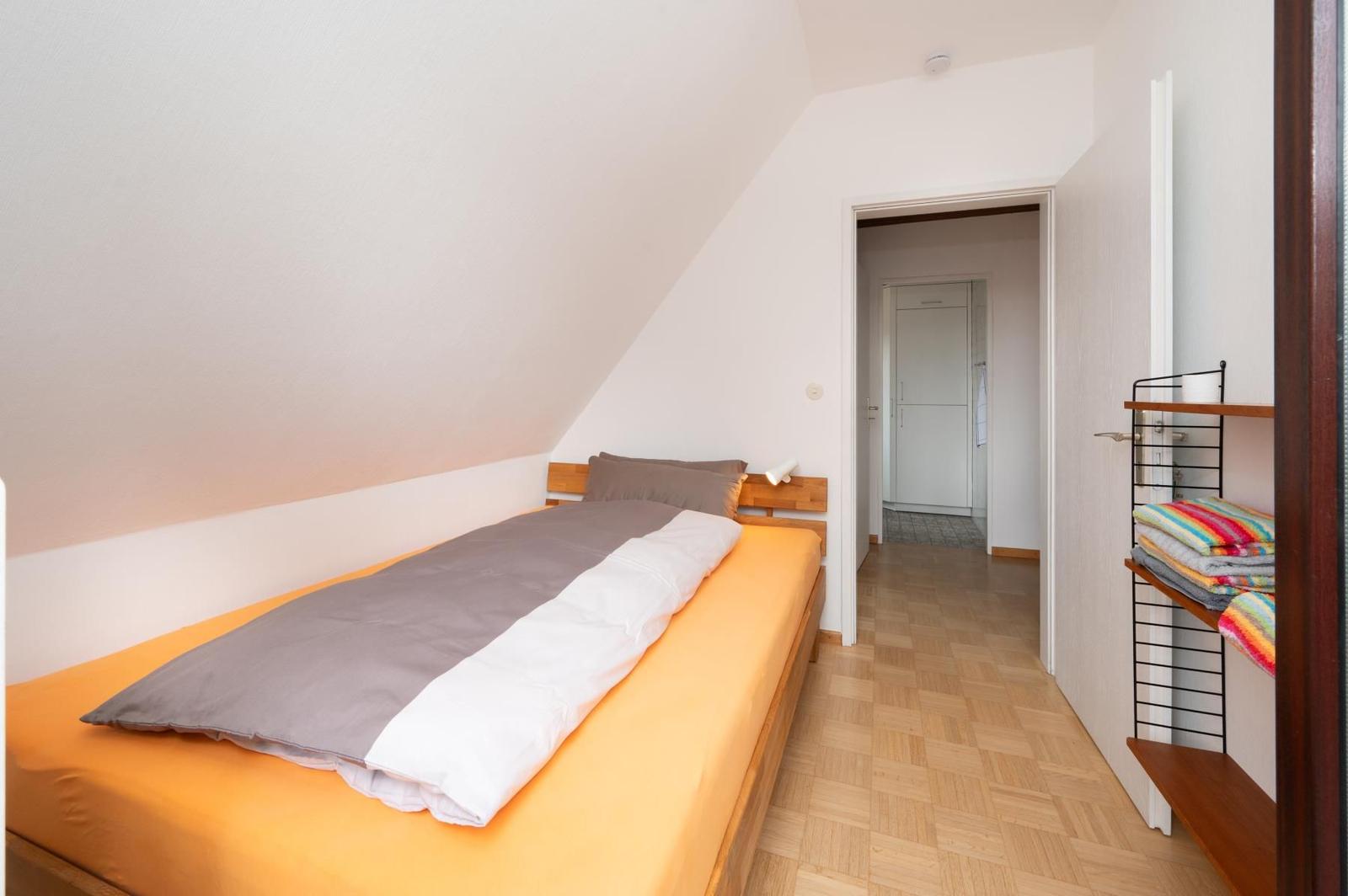 Schlafzimmer mit Dachschräge, Bett und Kleiderständer