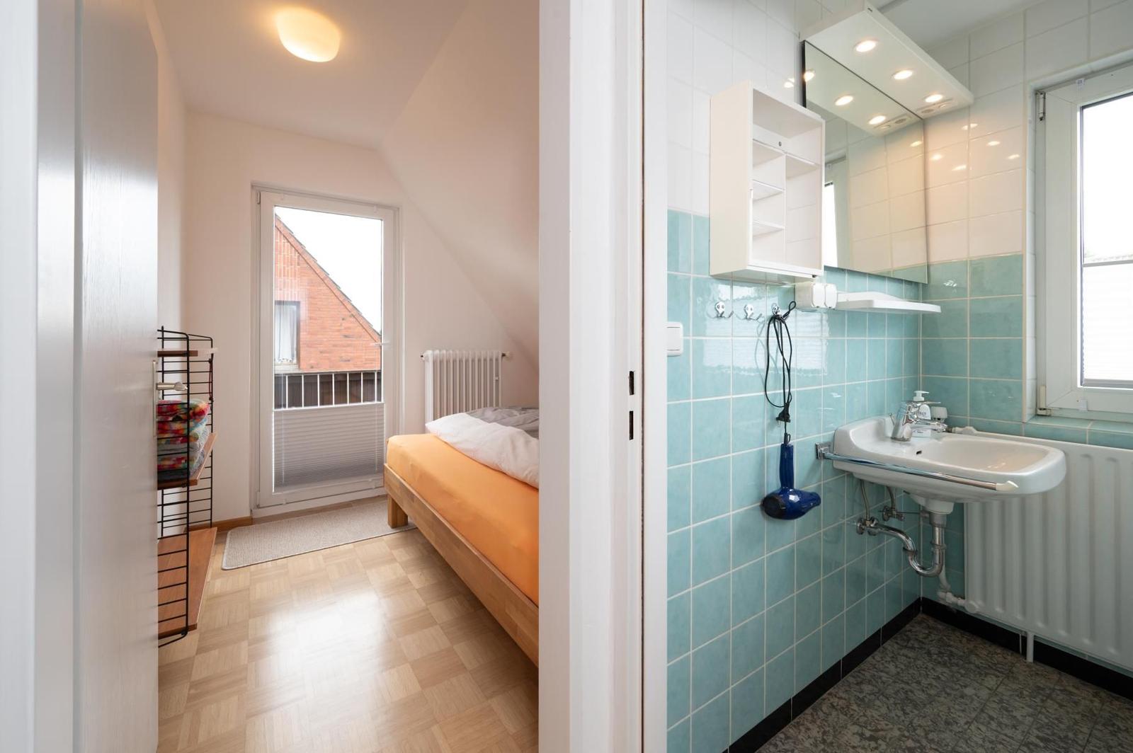 Schlafzimmer mit Balkon und angrenzende Bad mit Waschbecken