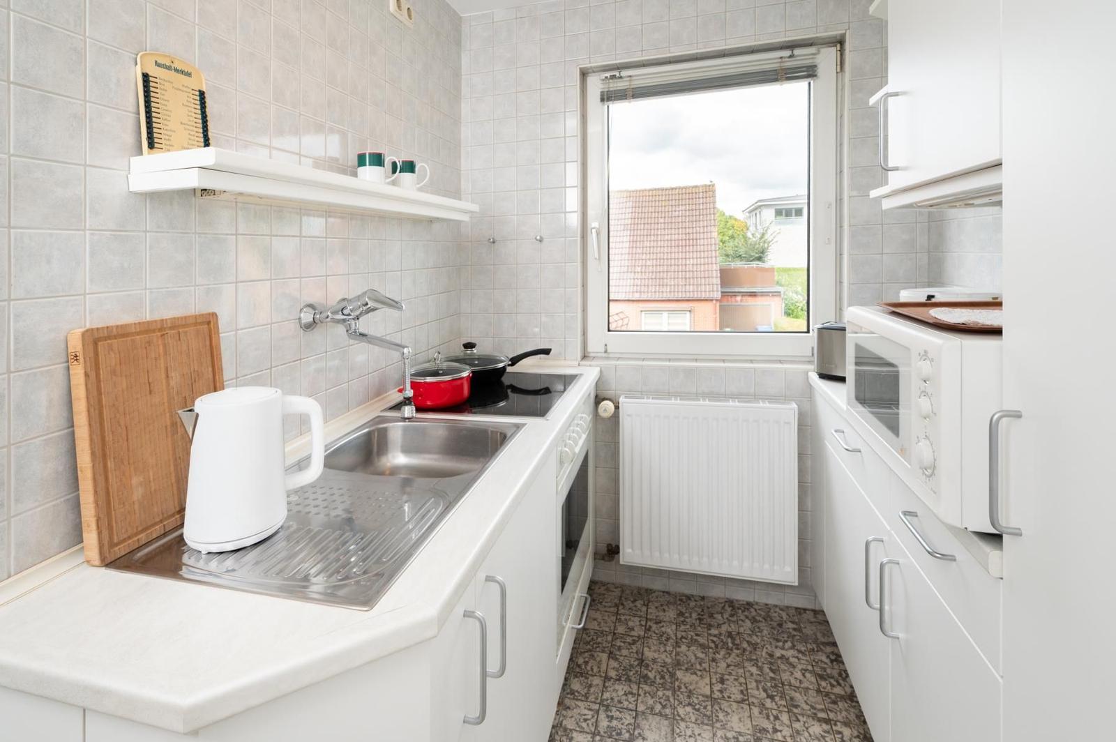 Küche mit Spüle, Herd, Kühlschrank und Fenster.