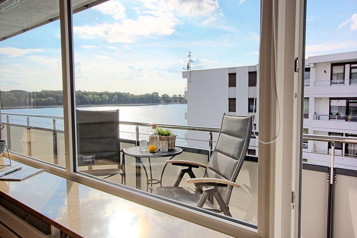 Balkon mit Sitzgelegenheiten und Blick auf Wasser und Gebäude.