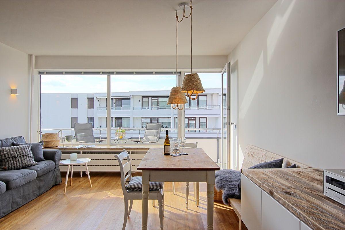 Wohn- und Essbereich mit Tisch, Stühlen und Balkonansicht.