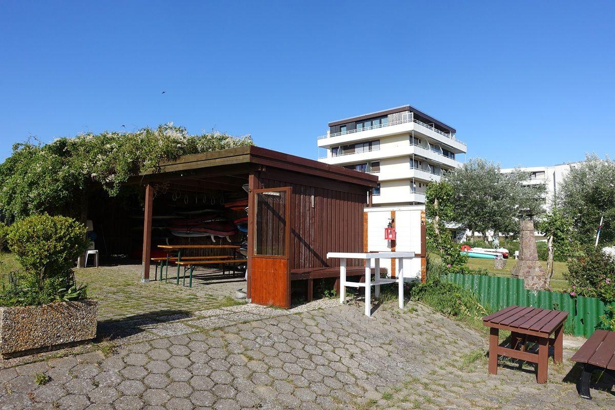 Terrasse mit Holzüberdachung, Tisch, Bänke und Bootsständer vor Wohnhaus