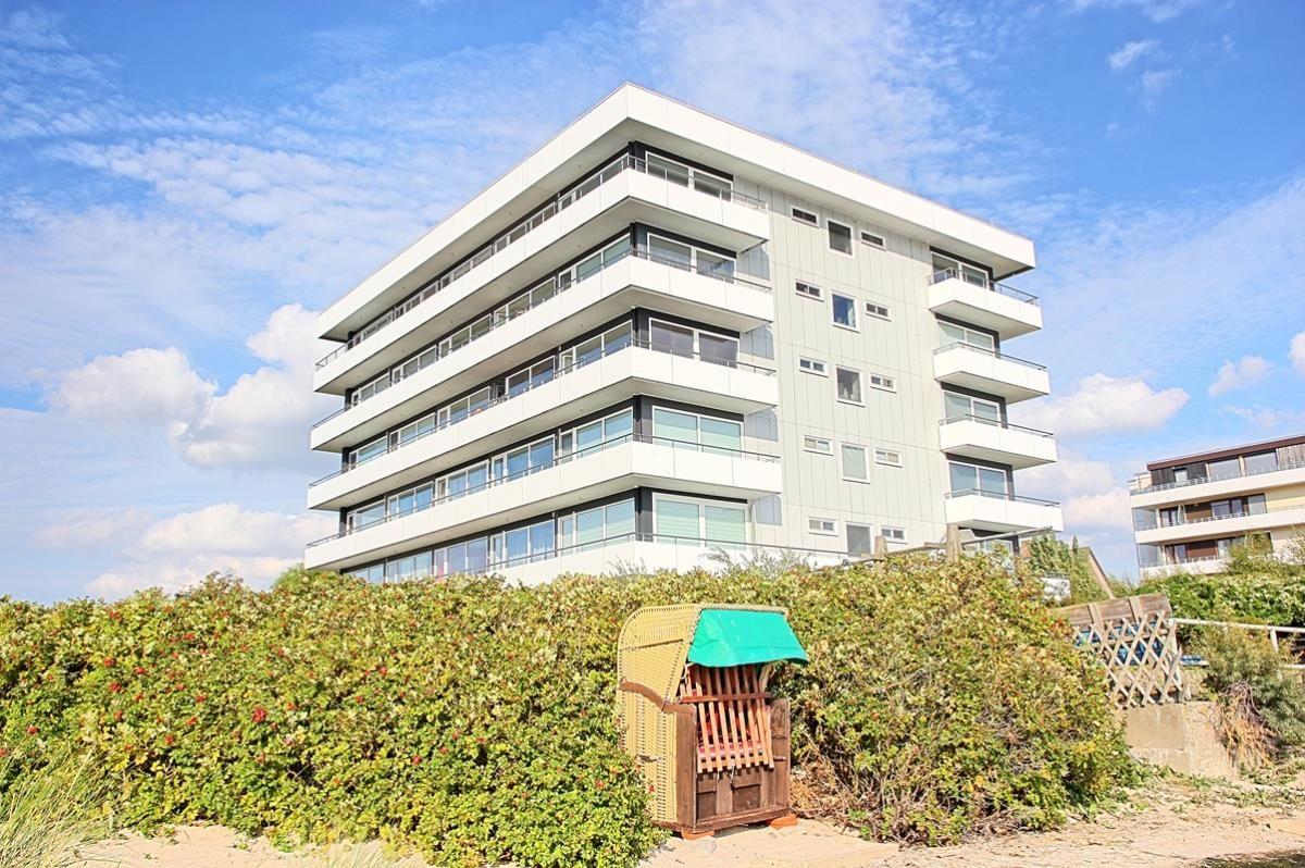 Moderne Mehrfamilienhaus mit Balkonen und Strandhütte im Vordergrund.