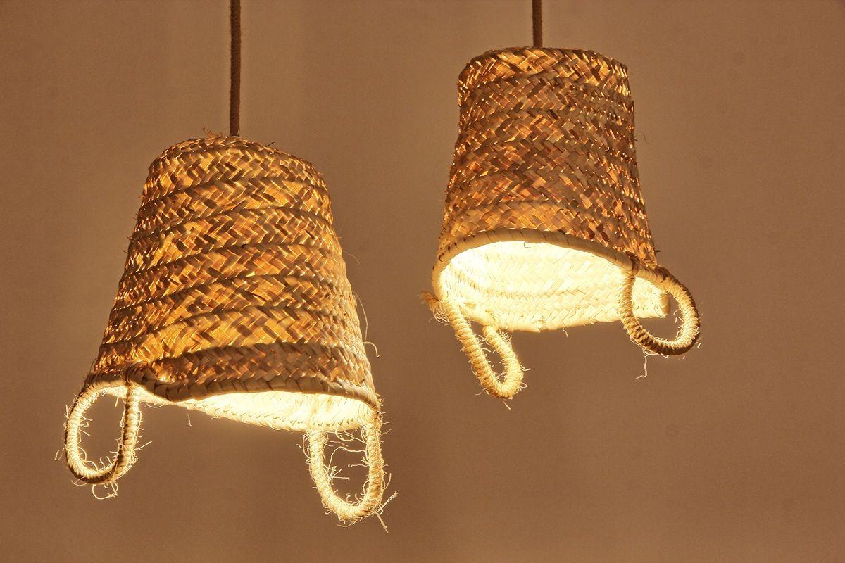 Zwei hängende, geflochtene Lampenschirme aus Naturmaterial mit Lichtquellen darin.