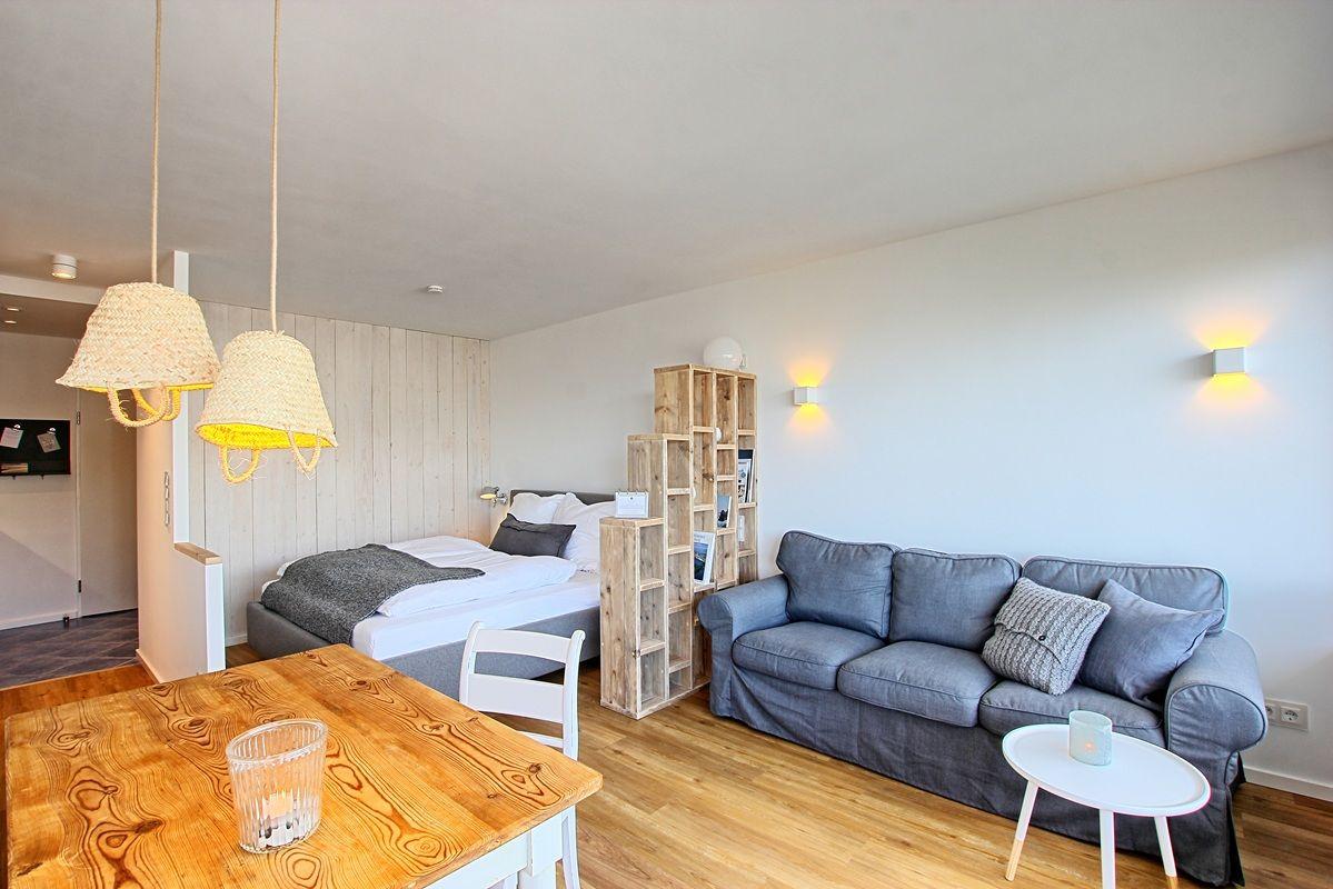 Ein Raum mit Sofa, Bett, Esstisch und Holzwand.