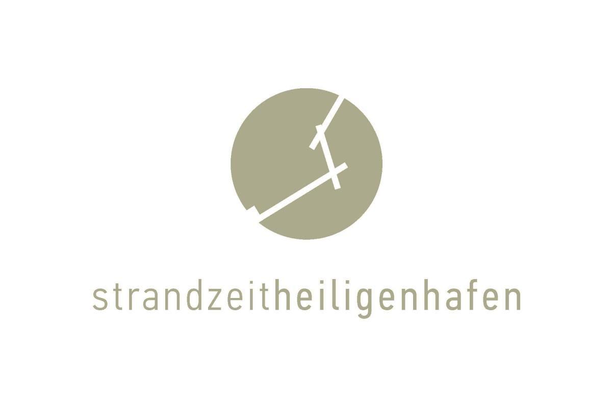 Logo mit Kreis und stilisiertem Schiff, darunter der Schriftzug strandzeitheiligenhafen.