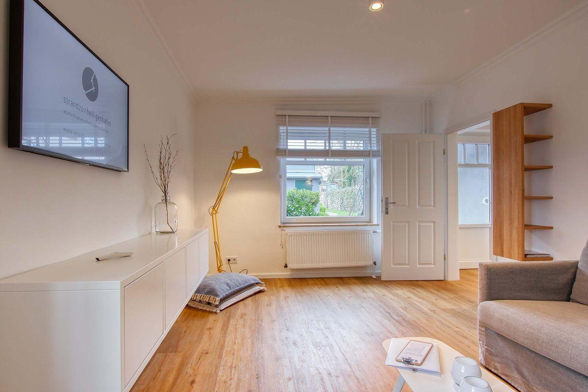 Wohnzimmer mit Fernseher, Sofa, Holzboden und Fenster.