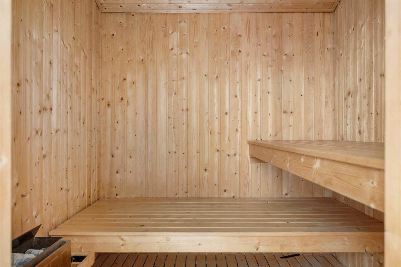 Holzsauna mit zwei Sitzbänken und Bodenbelag.