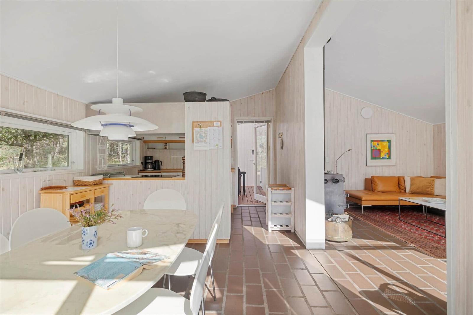 Essbereich mit Küchenzeile und Wohnzimmer mit Sofa und Teppich.